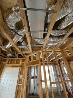 A room in a house under construction with a lot of pipes coming out of the ceiling.