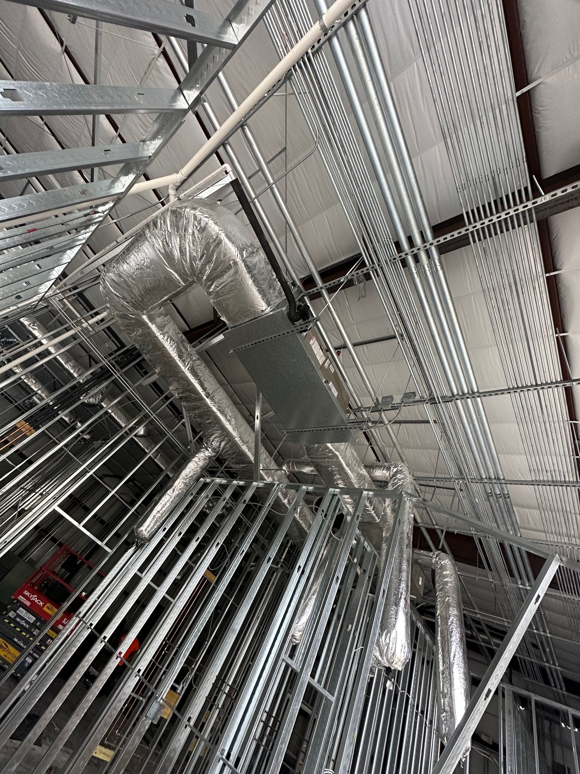 A ceiling with a lot of metal pipes hanging from it.