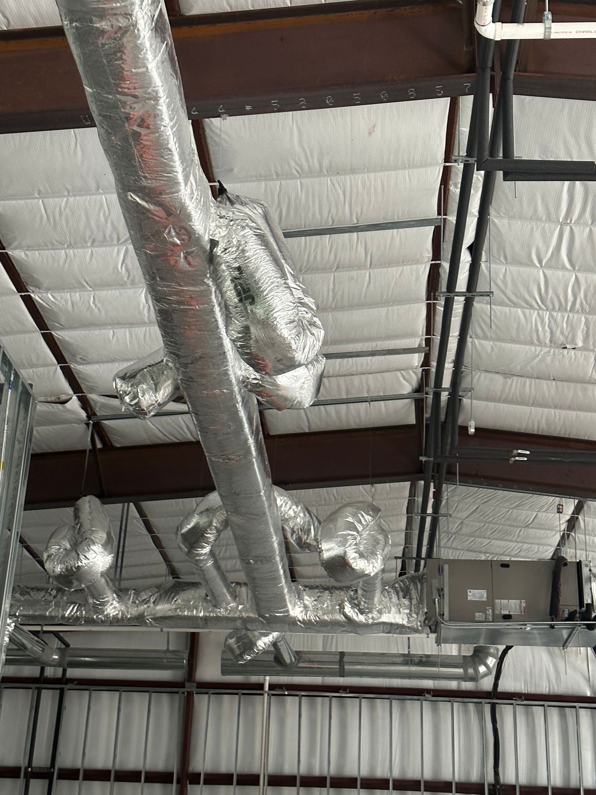 There are a lot of pipes hanging from the ceiling of a building.