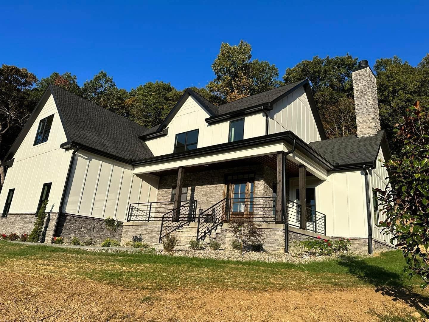 A large white house with a black roof is sitting on top of a hill.