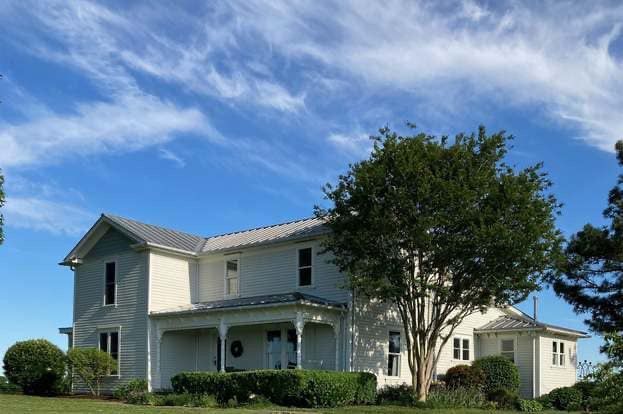 A large white house with a porch and a tree in front of it