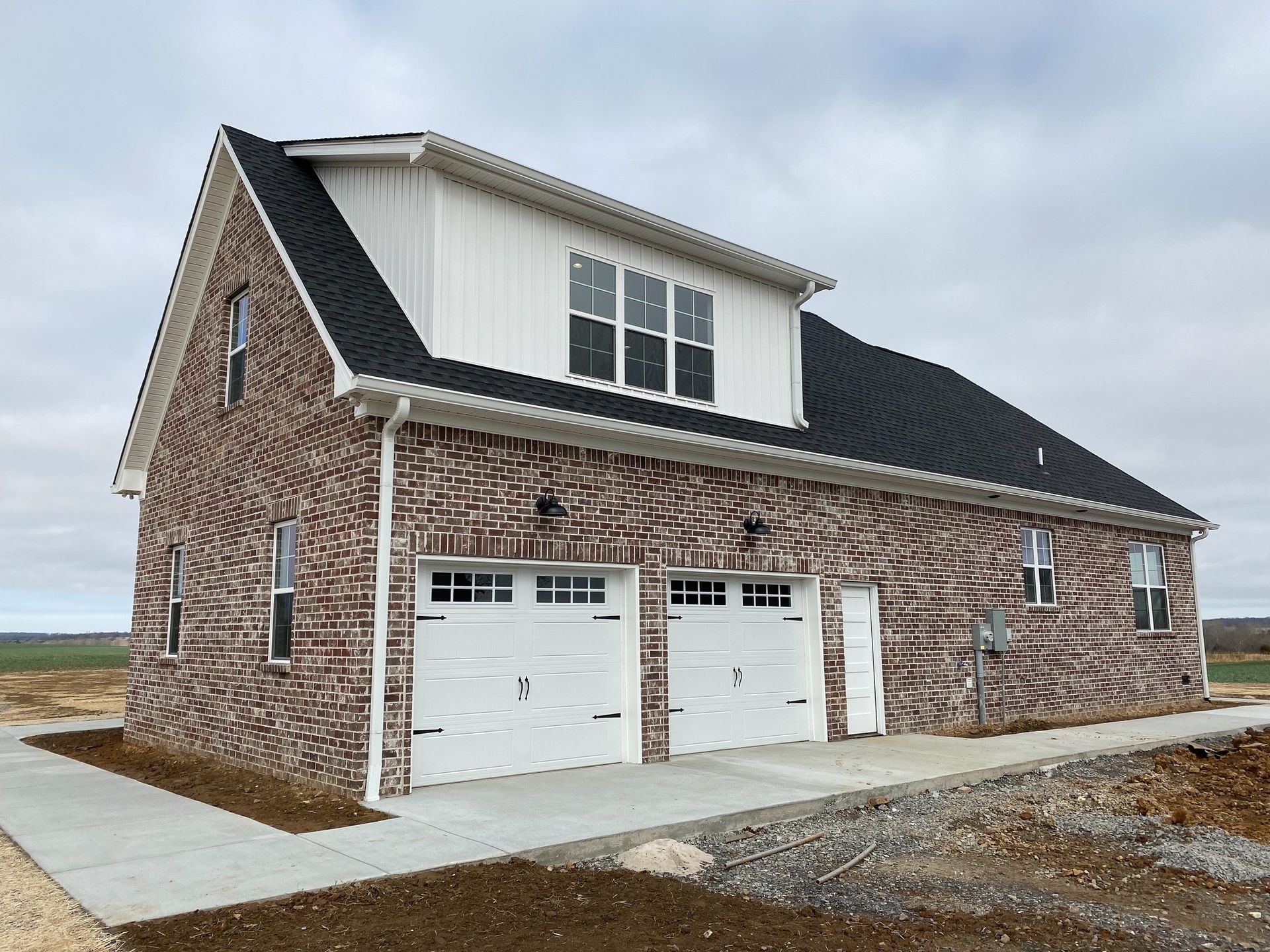 A large brick house with two garage doors and a black roof.