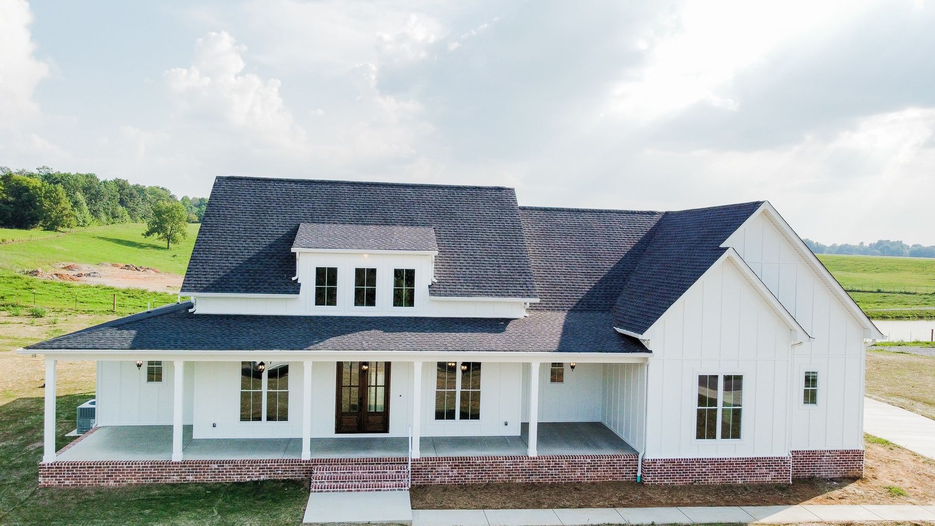 A large white house with a black roof and a large porch.