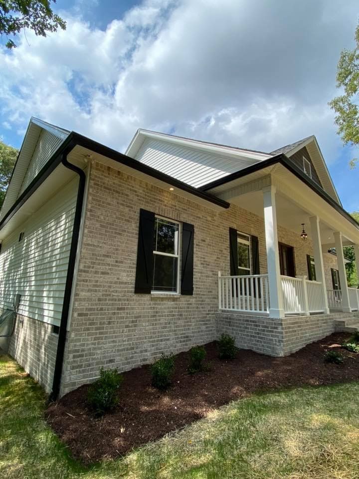 A white brick house with a porch and black shutters.
