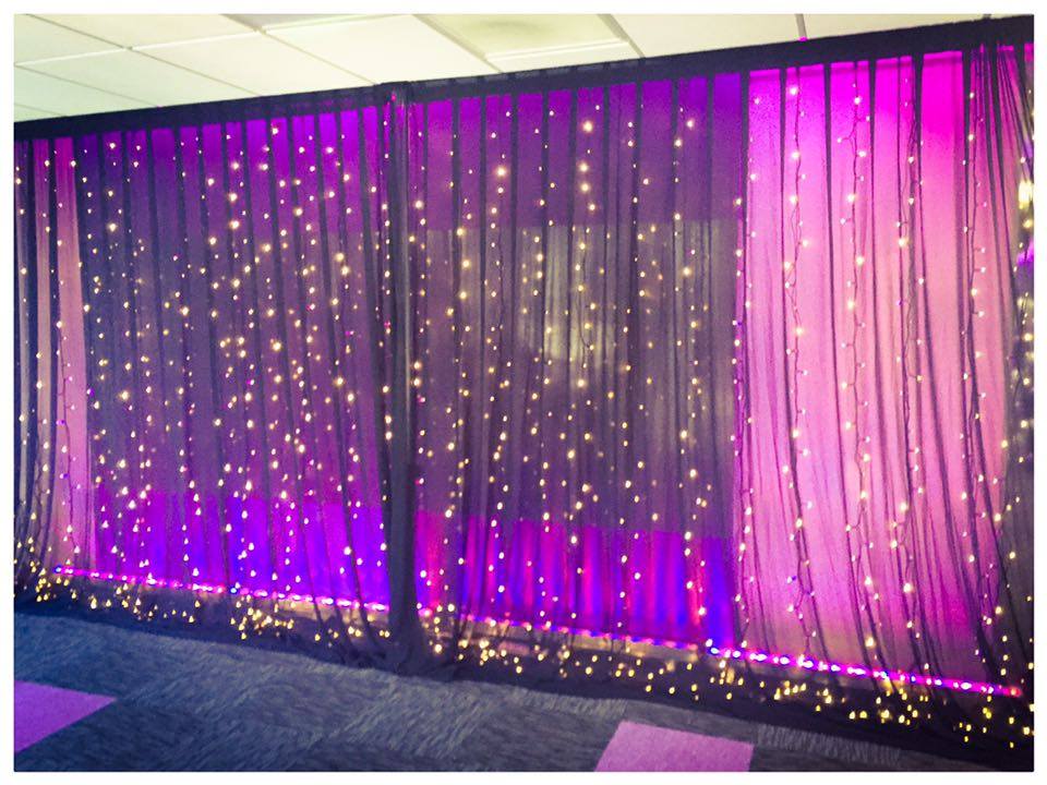 Purple wall wash lights under white chiffon drapes