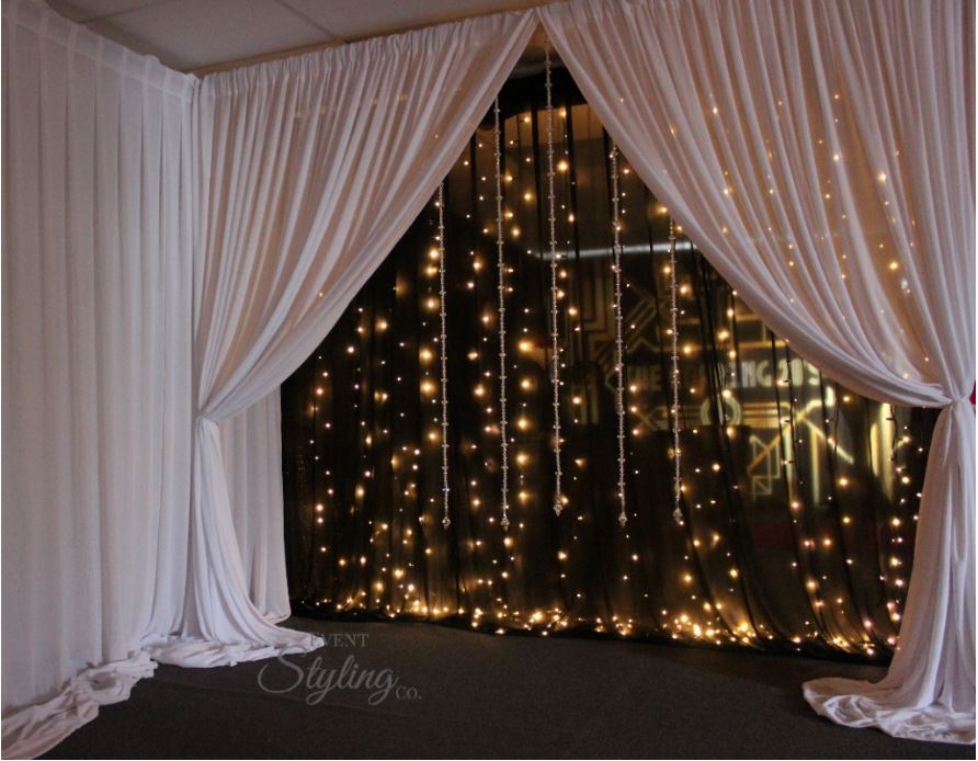 Bespoke black fairy light backdrop with white drapes and crystal starnds in front. Hire price from $450 including Auckland installation
