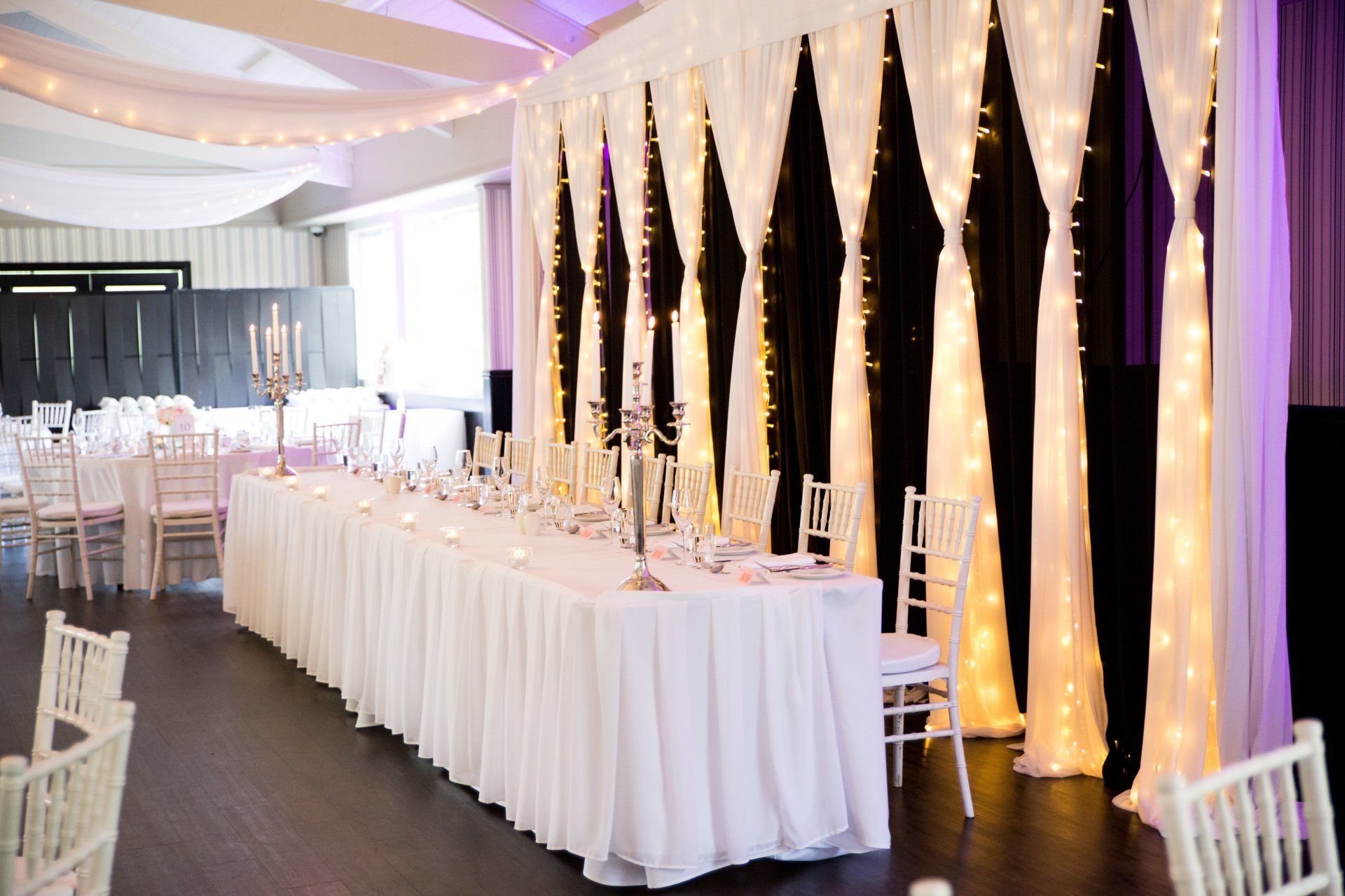 Milan black and white fairy curtain backdrop shown with warm white fairy lights at a wedding at Bracu
