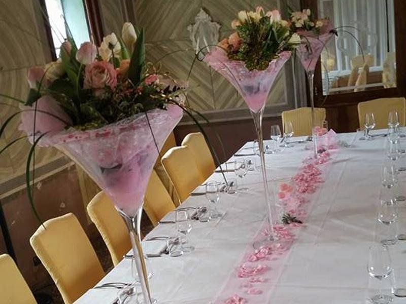 Tavolo allestito con vasi di fiori e decorazioni rosa