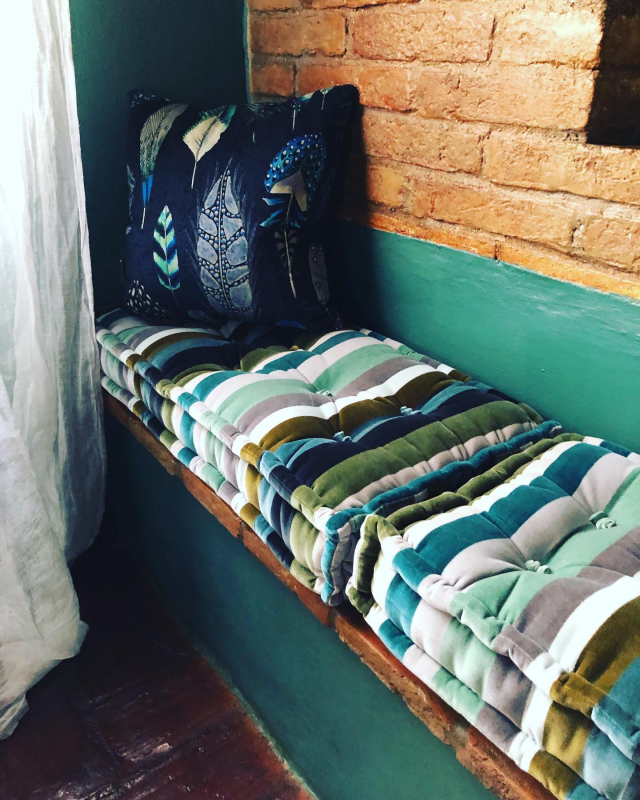 Accogliente panca vicino alla finestra con cuscini a righe e un cuscino decorato.