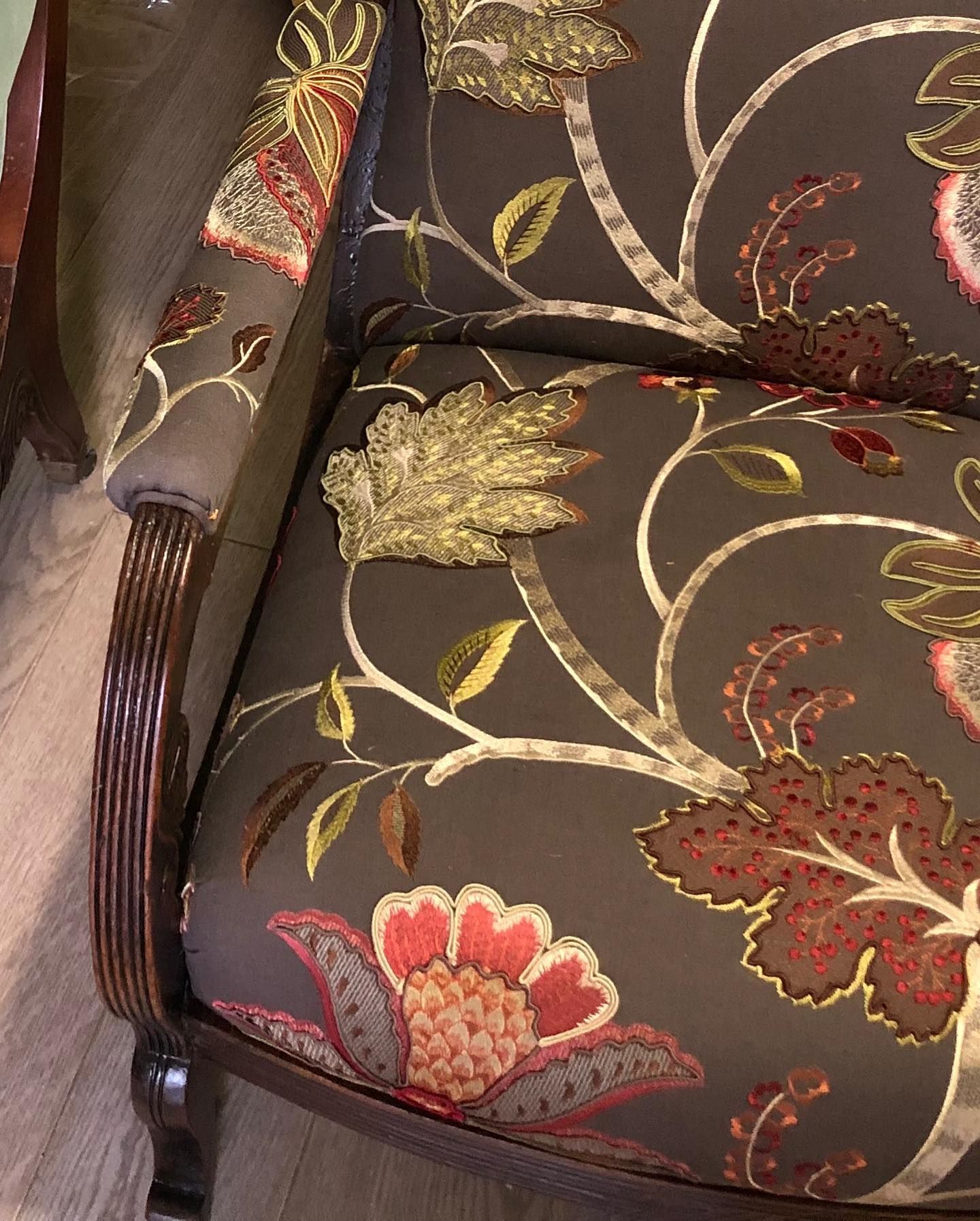 Poltrona con motivo floreale su tessuto marrone scuro.