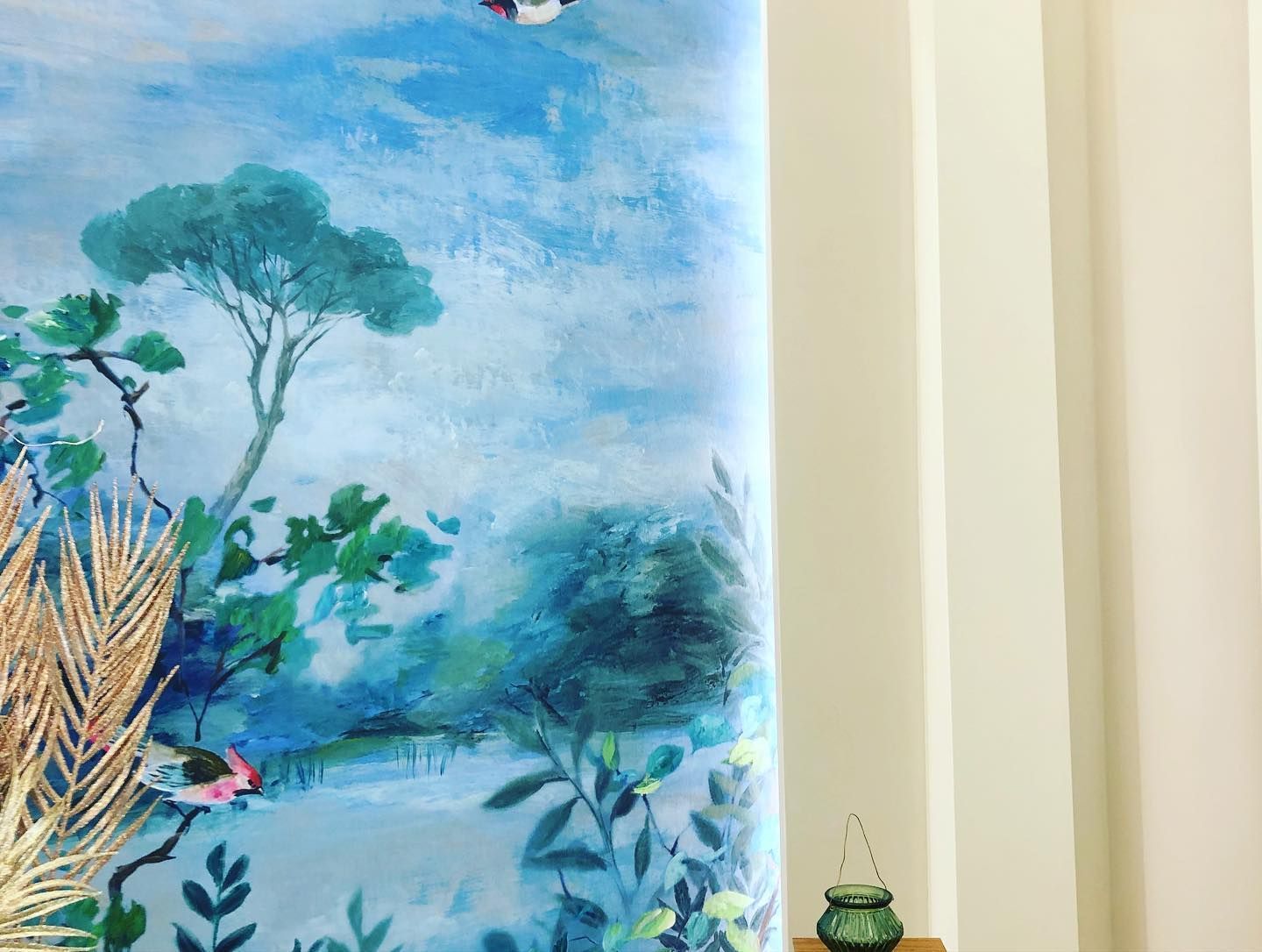 Due poltrone in velluto blu con braccioli angolari sono appoggiate su un pavimento in legno. Una ha un cuscino coordinato.