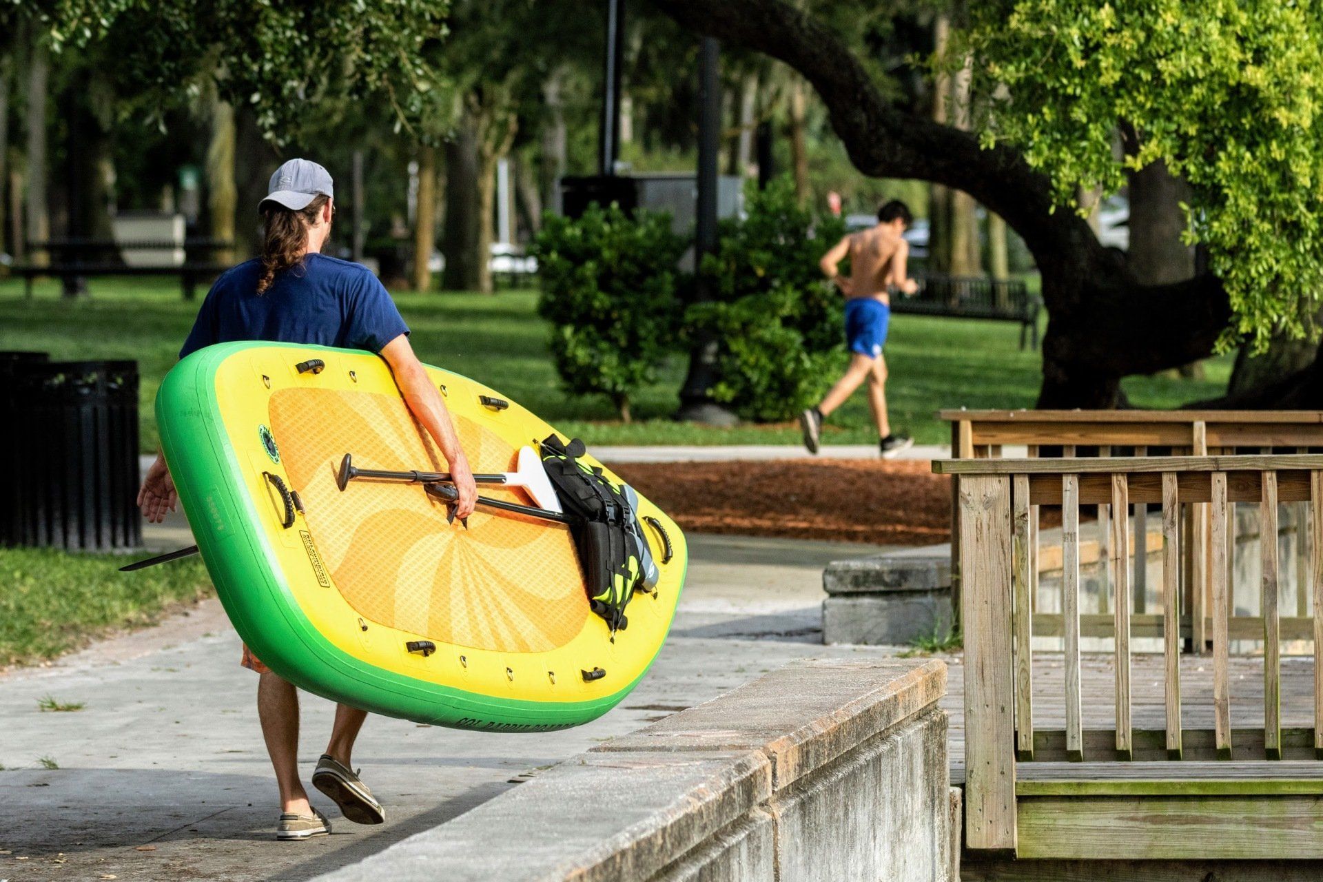 A person holding a watersport craft and walking along the water