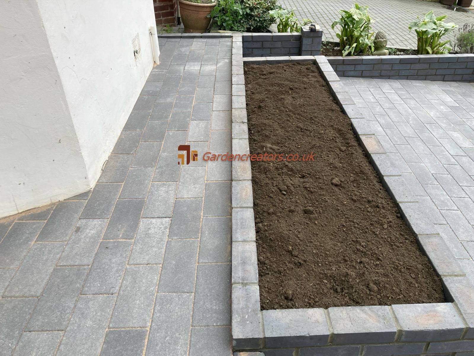 A brick walkway with a planter in the middle of it