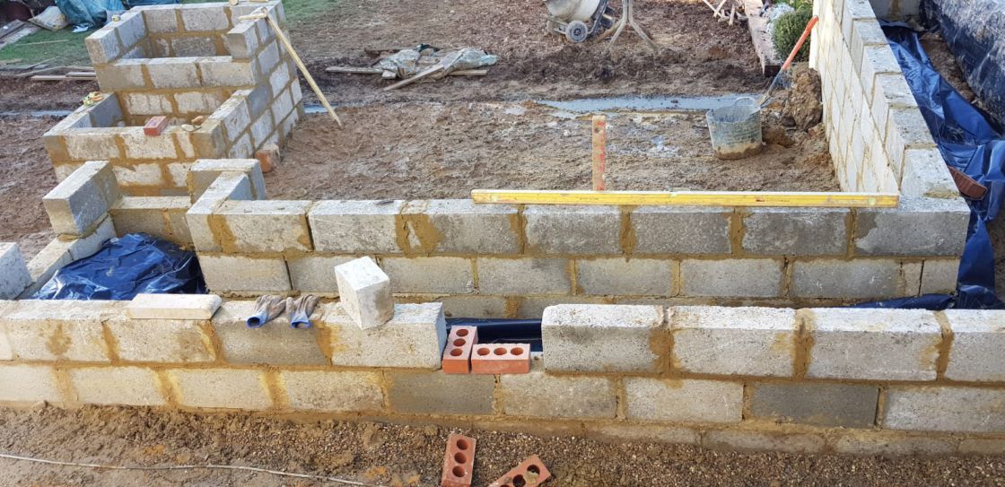 A brick wall is being built with a yellow ruler.