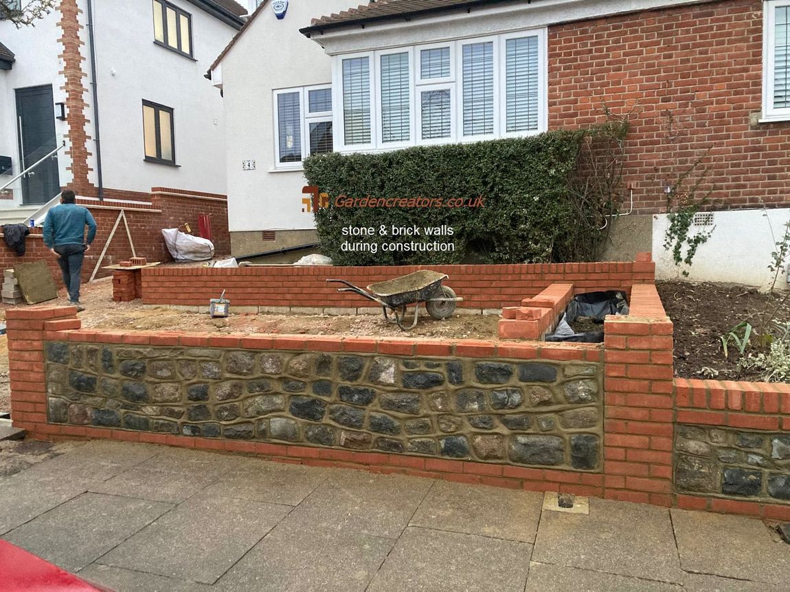 A brick wall is being built in front of a house.