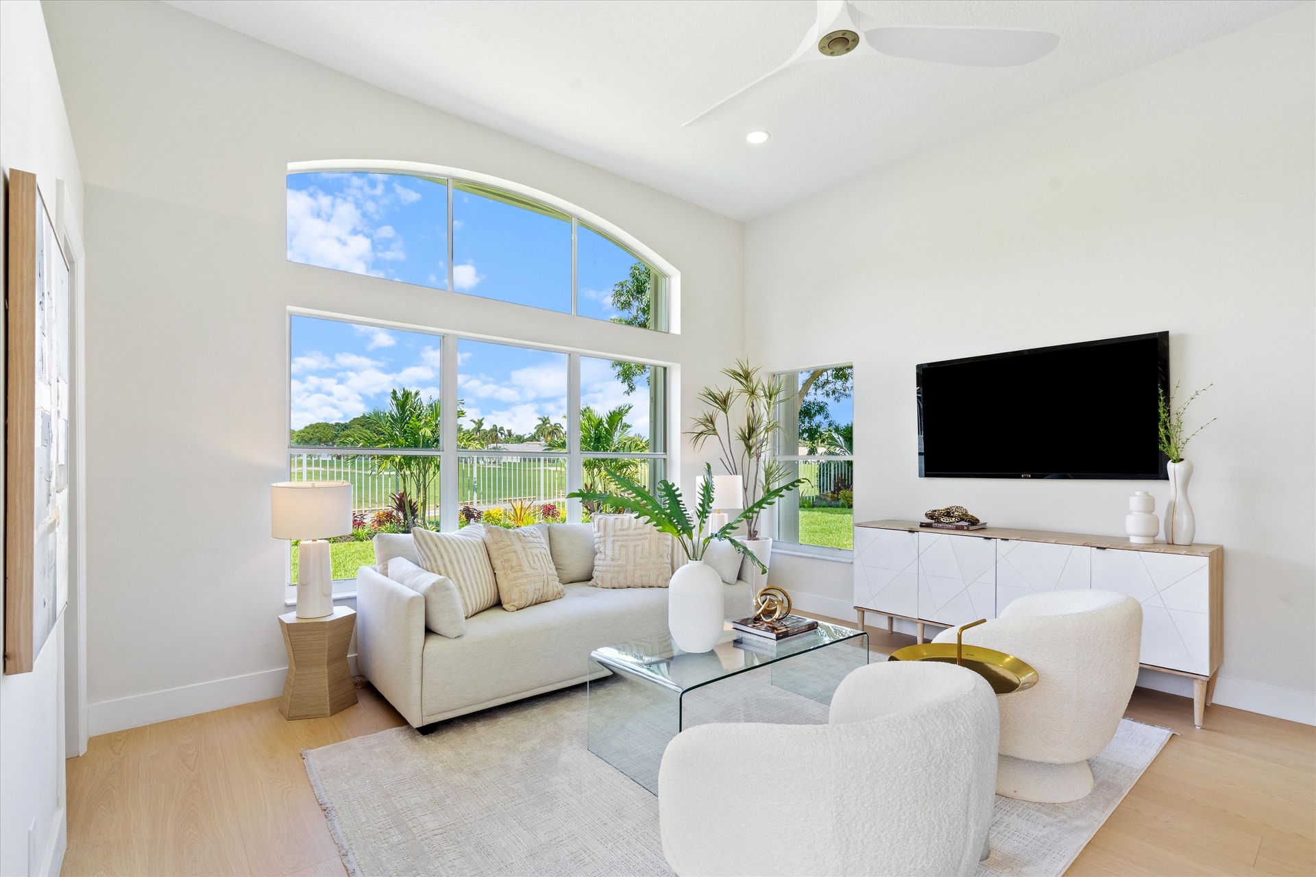 A living room with a couch , chairs , and a flat screen tv.