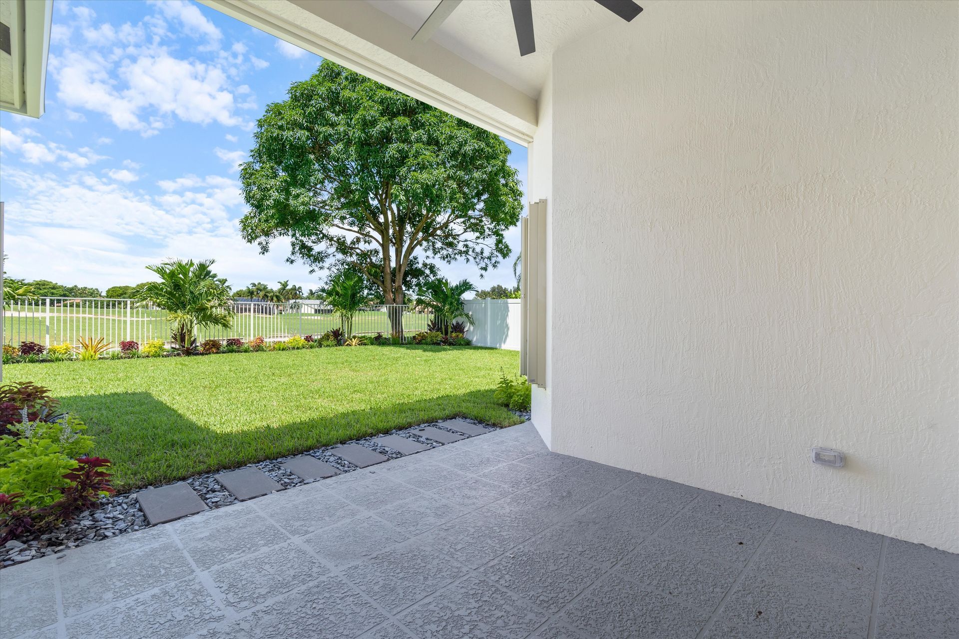 An empty patio with a view of a backyard and a tree