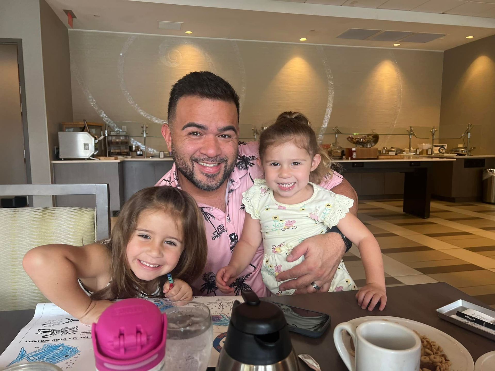 A man is sitting at a table with two little girls.