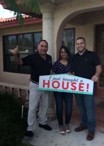 Three people holding a sign that says i just bought a house