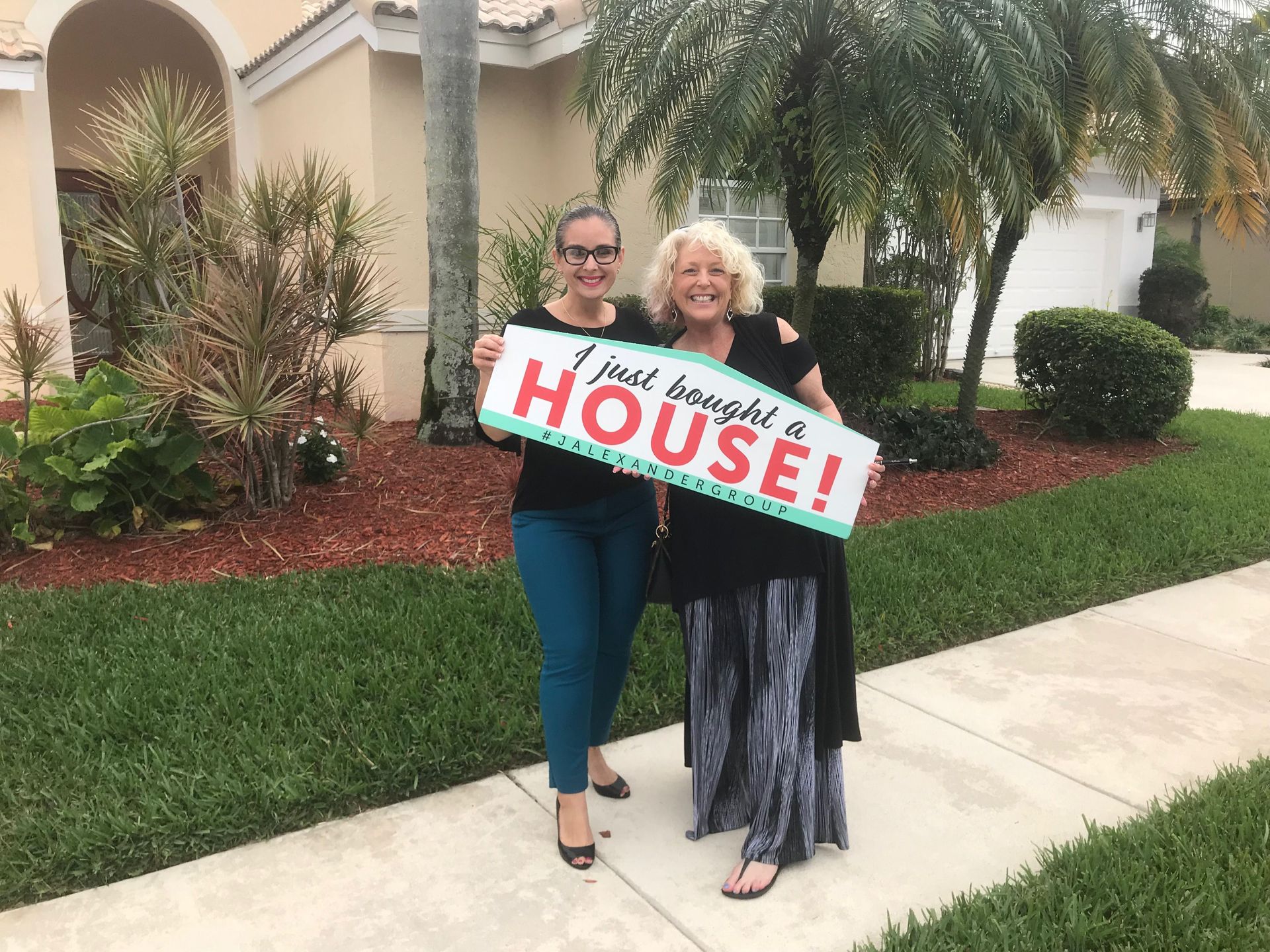 Two women are holding a sign that says i just bought a house.