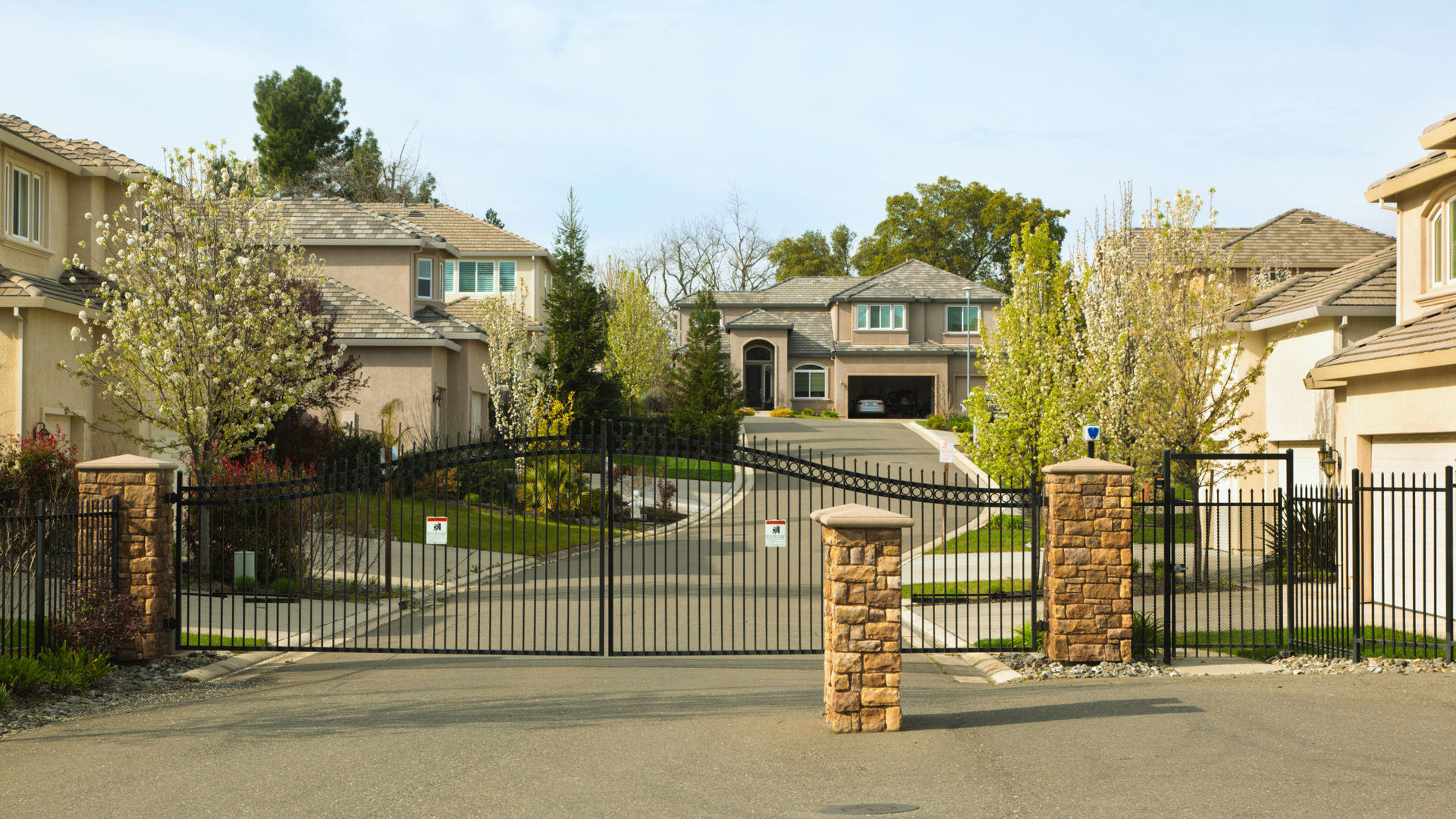 A gated entrance to a residential neighborhood with houses in the background