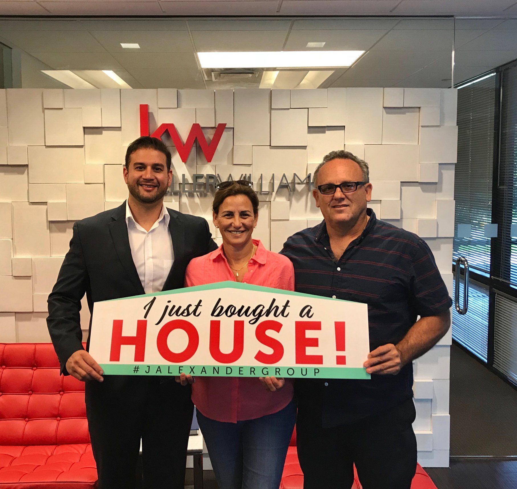 Three people holding a sign that says i just bought a house