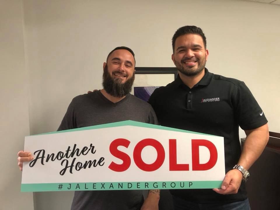 Two men are holding a sign that says another home sold