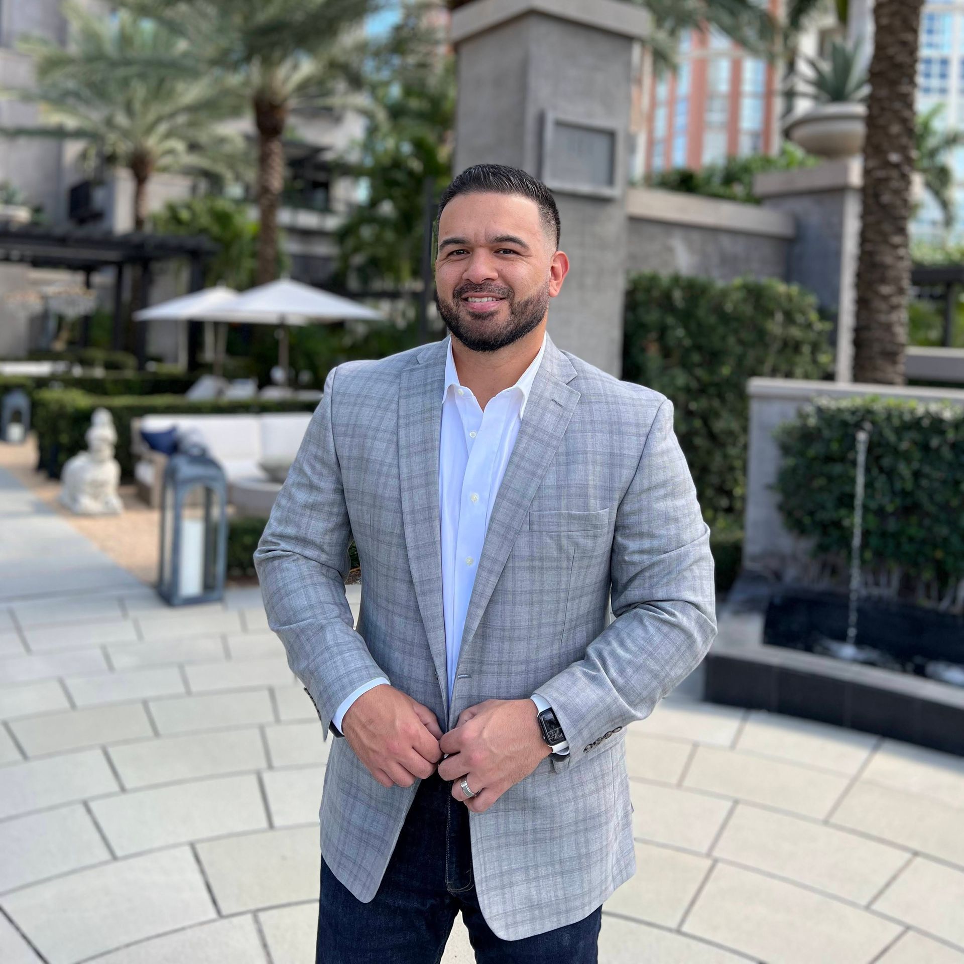 A man in a suit jacket and white shirt is standing on a sidewalk.