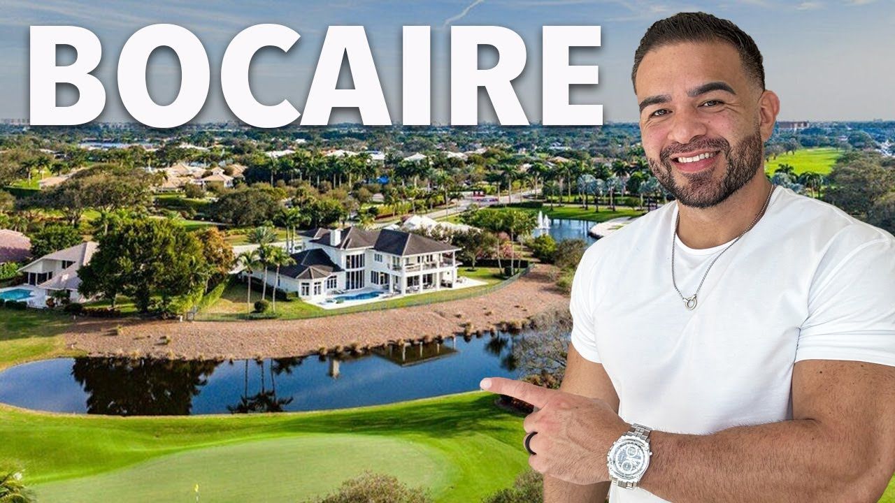 Man points at luxurious Bocaire home with golf course and lake.