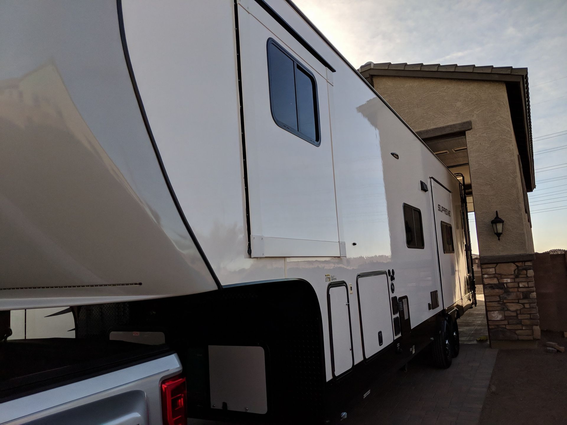 A white trailer is parked in front of a building with Bob Moses ceramic coating, Sensha World Crystal Glow