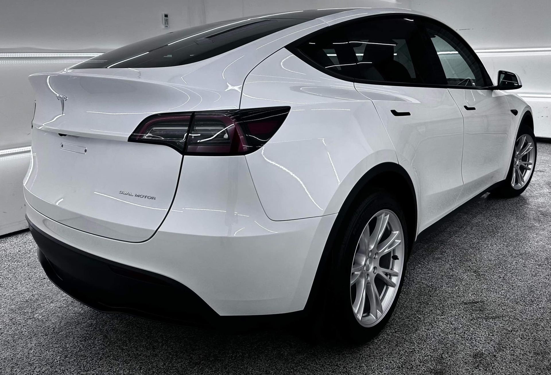 A white tesla model y is parked in a garage.