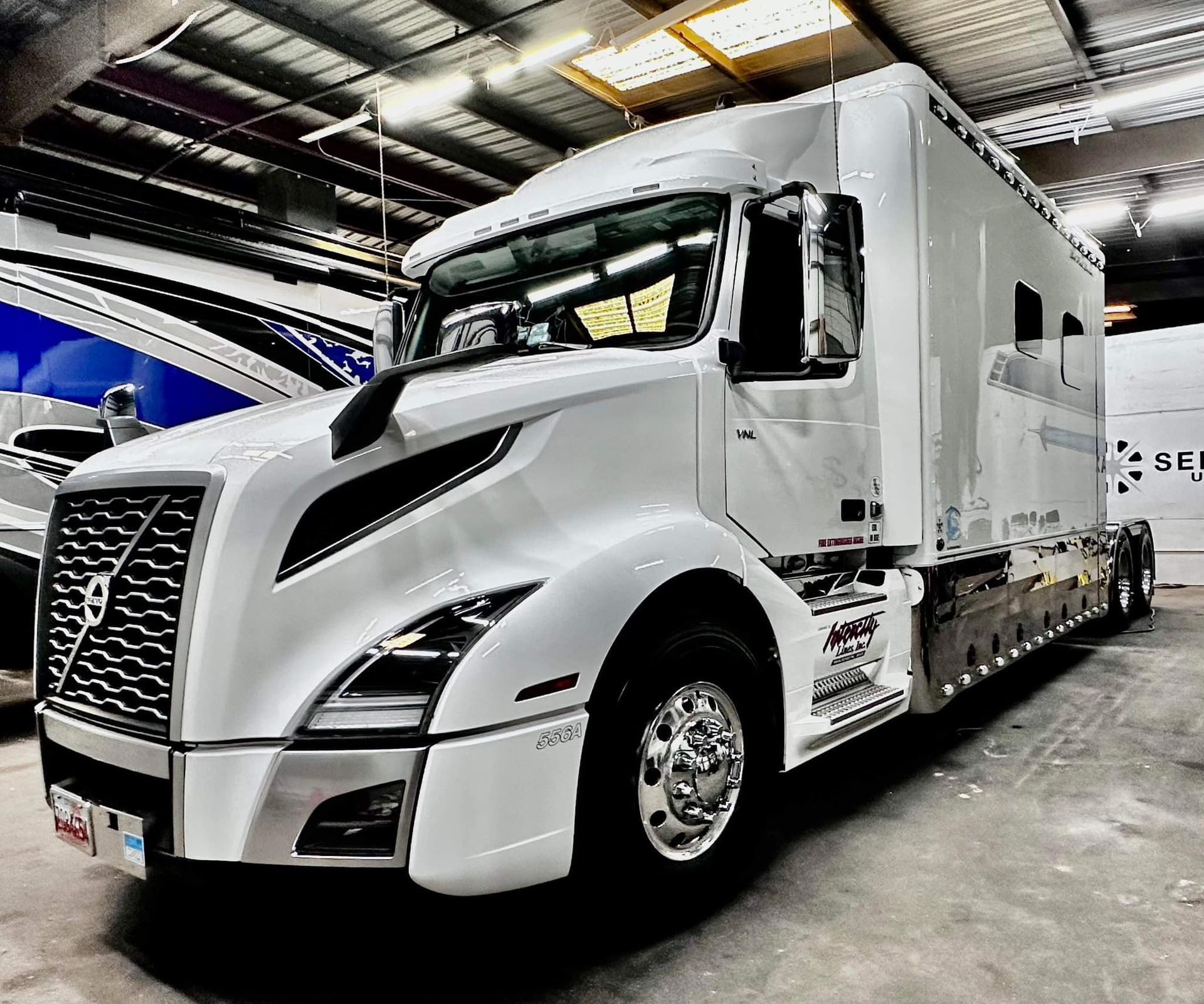 A white semi truck is parked in a warehouse with Bob Moses ceramic coating, Sensha World Crystal Glow
