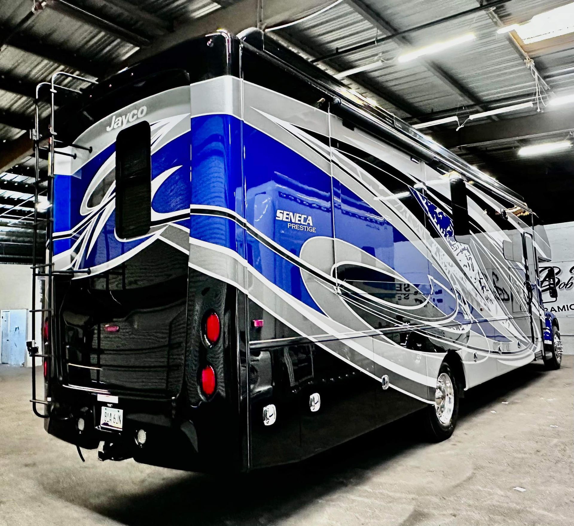 A blue and silver rv is parked in a garage.