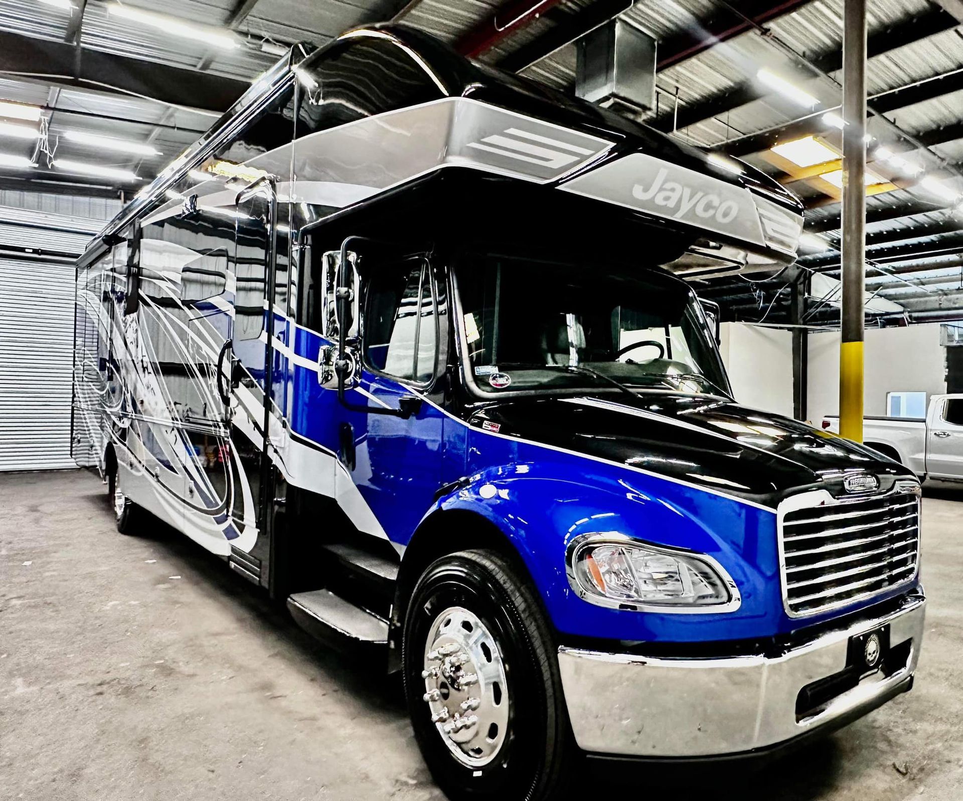 A blue and white bus is parked in a garage.