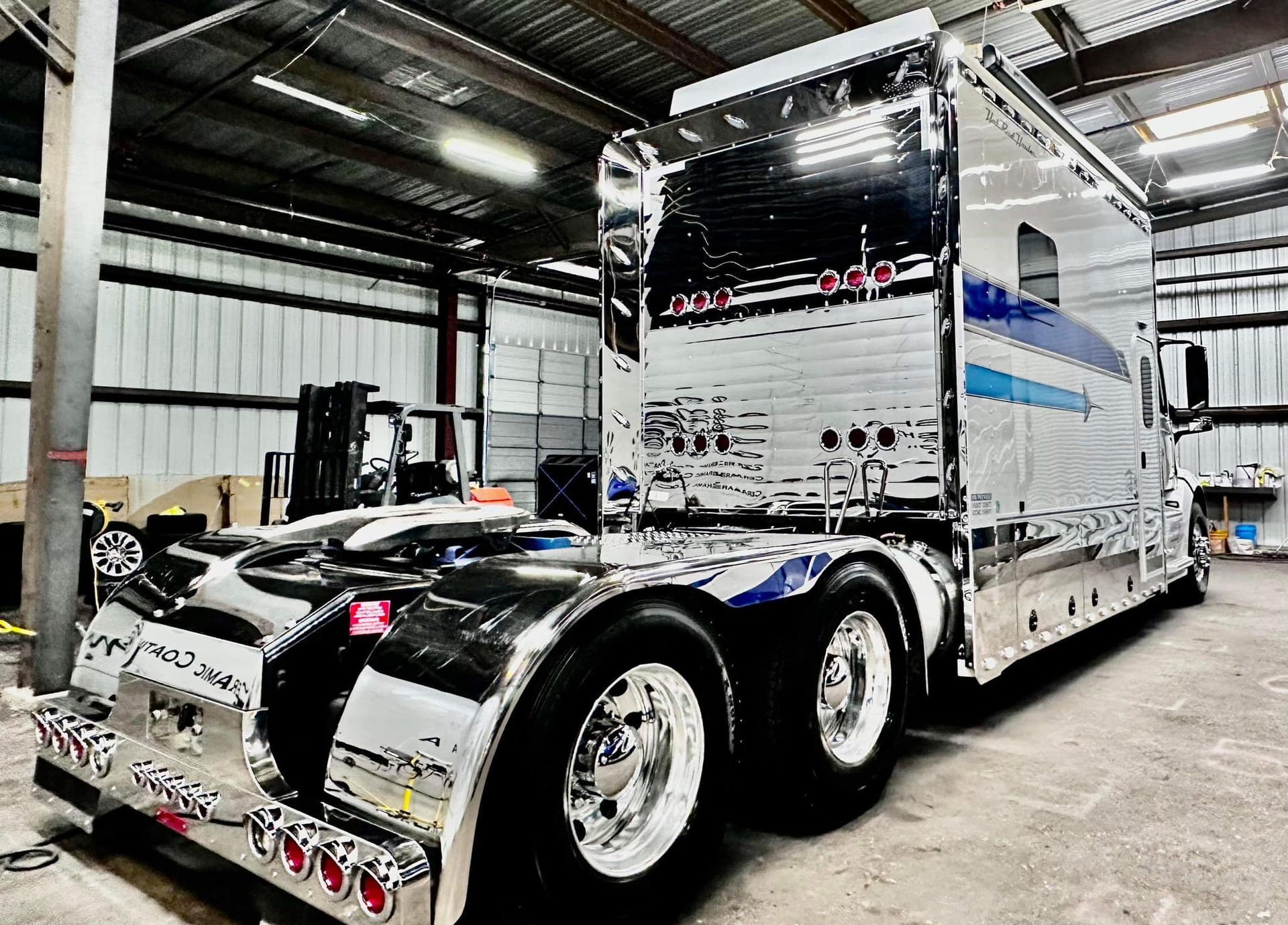 A large truck is parked in a garage with a trailer attached to it with Bob Moses ceramic coating, Sensha World Crystal Glow