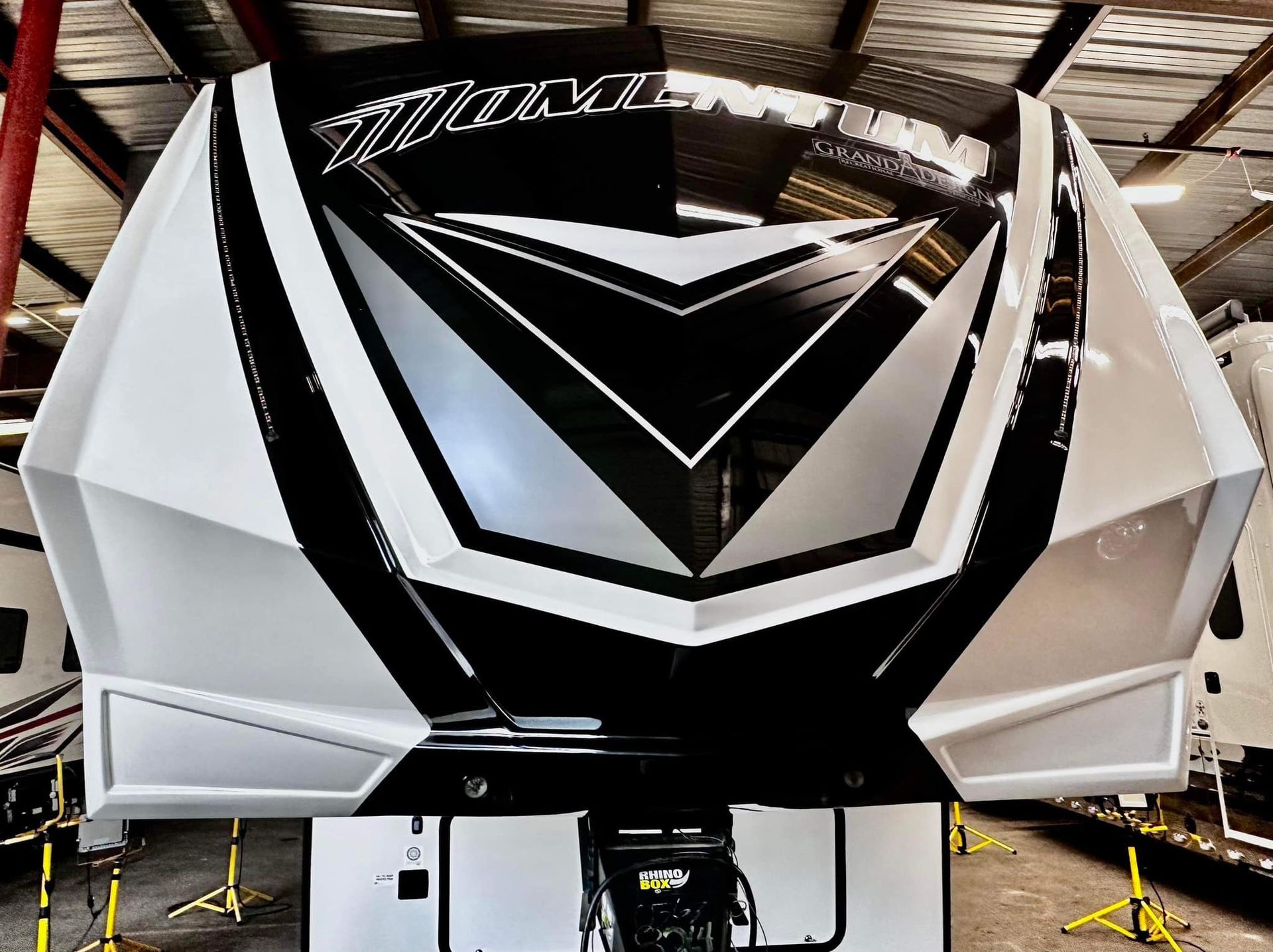 A black and white rv is parked in a warehouse with Bob Moses ceramic coating, Sensha World Crystal Glow