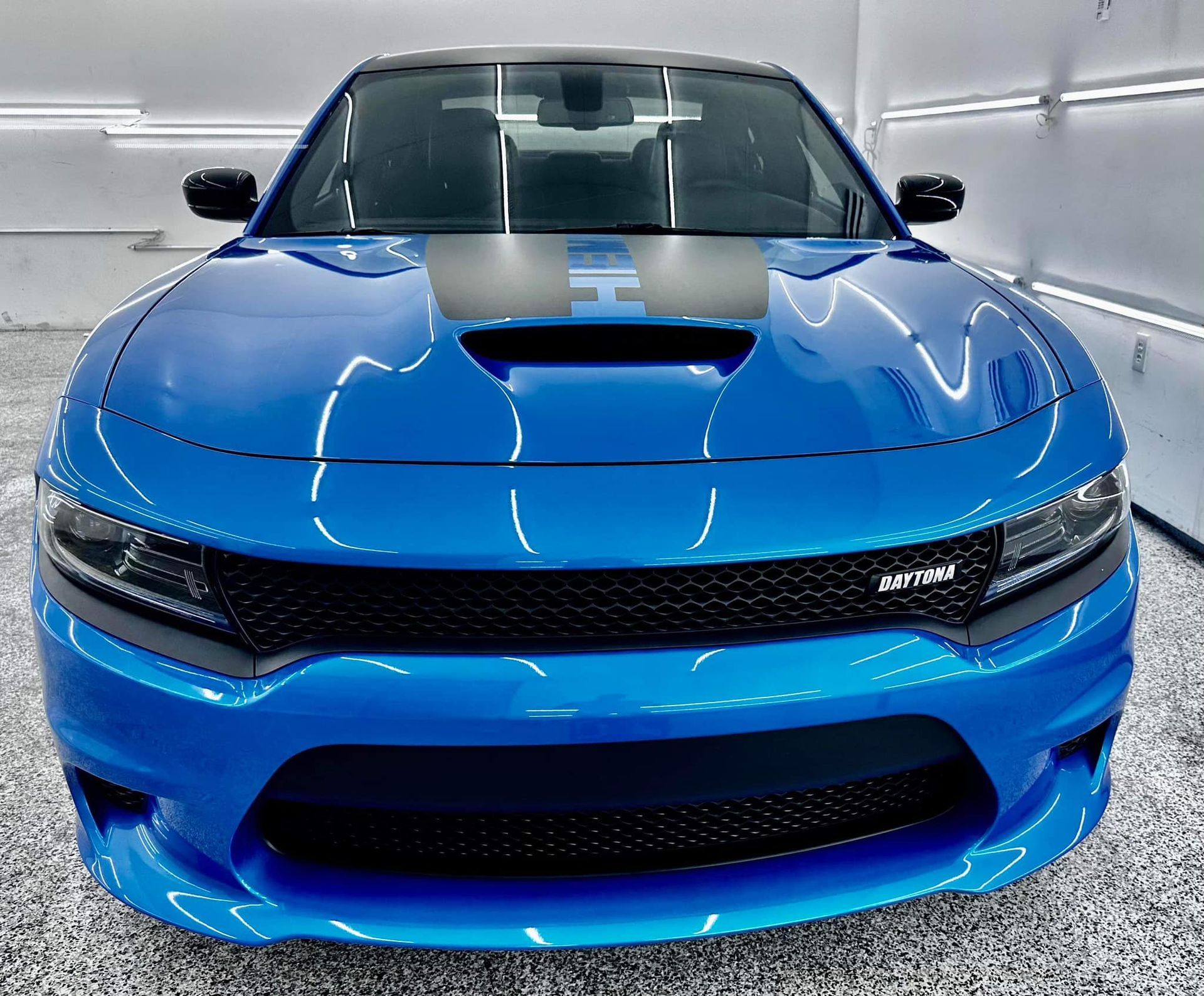 A blue dodge charger is parked in a garage
