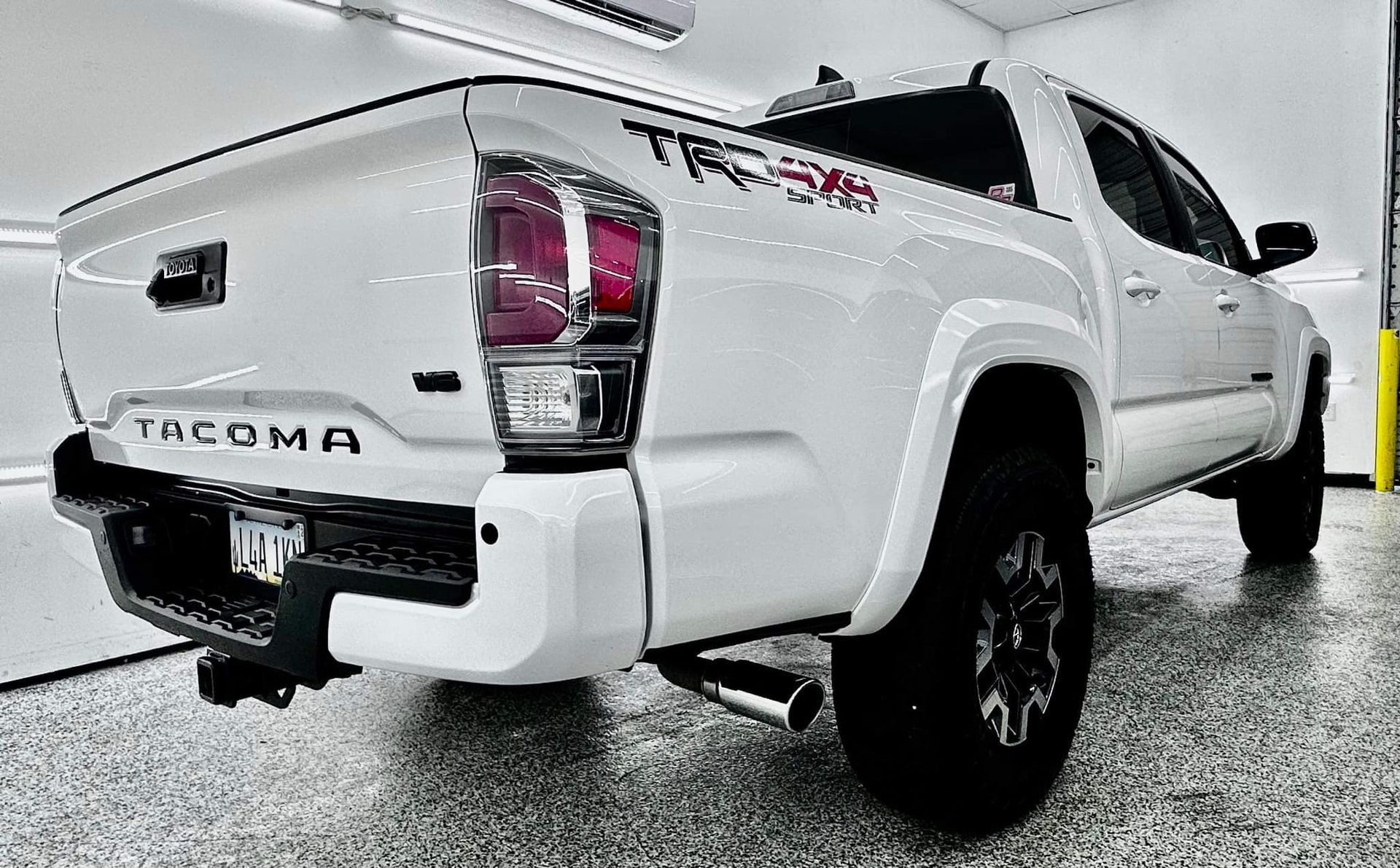 A white toyota tacoma truck is parked in a garage.