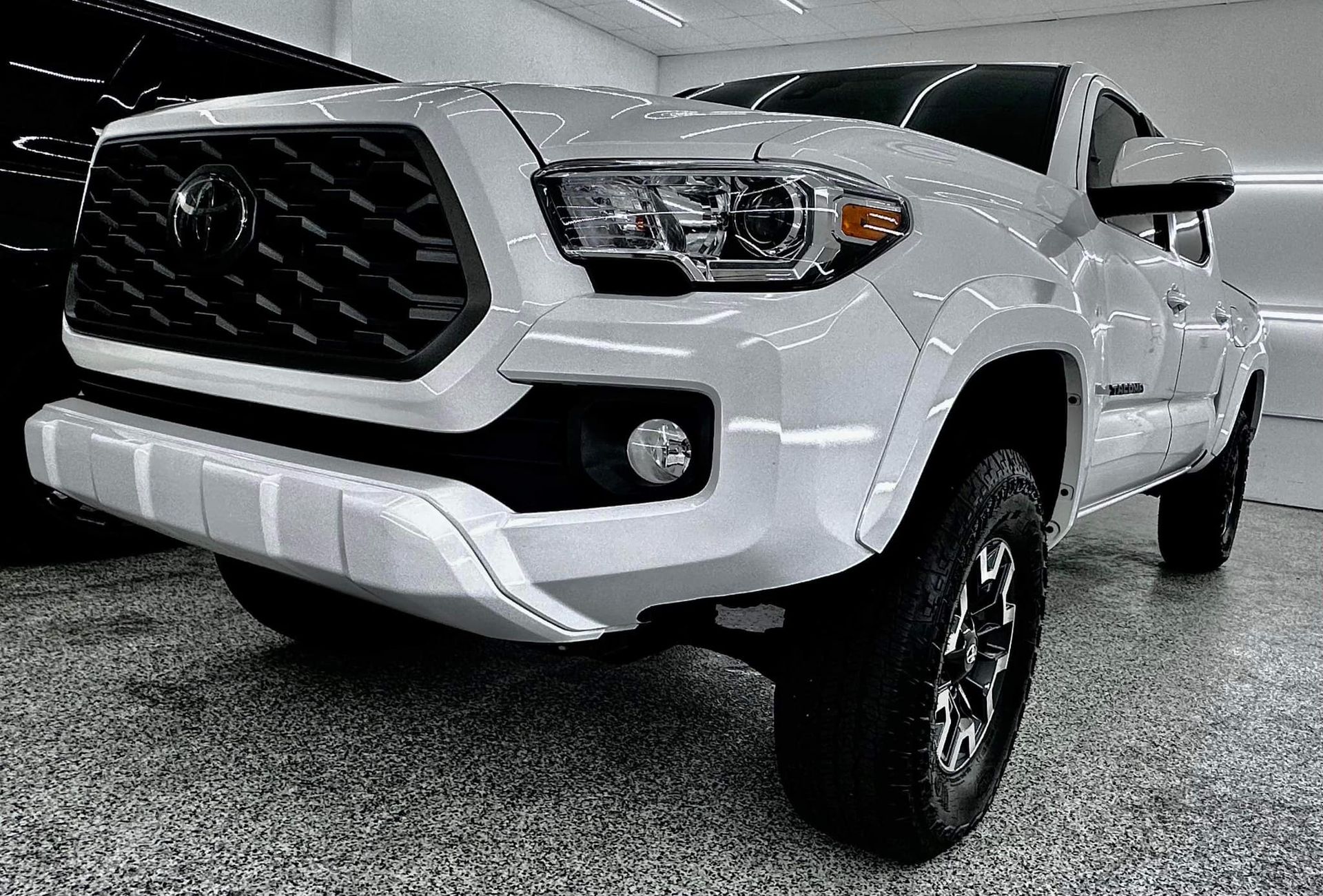 A white toyota tacoma truck is parked in a garage.
