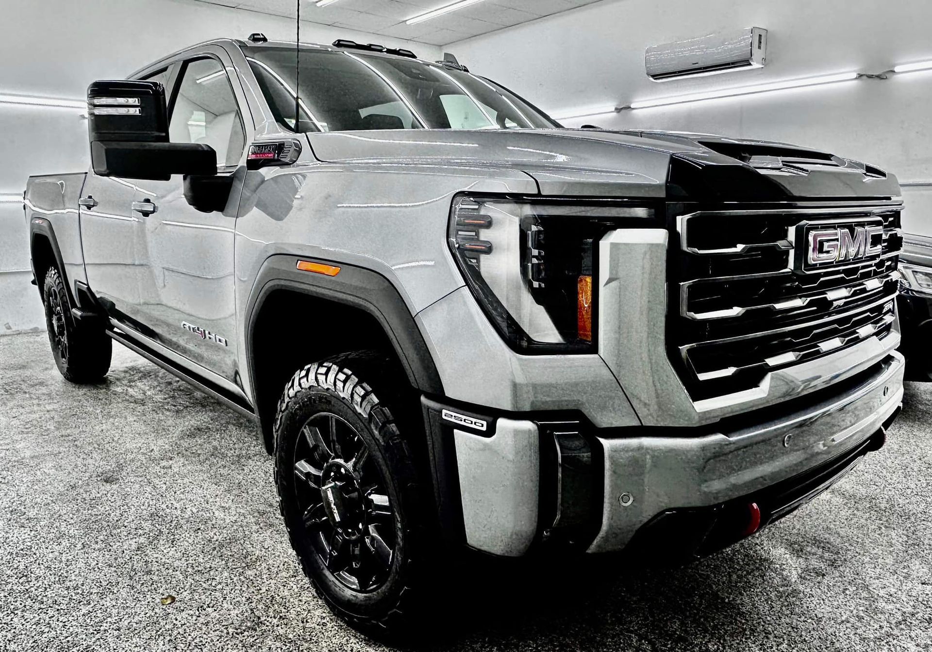 A silver gmc truck is parked in a garage.