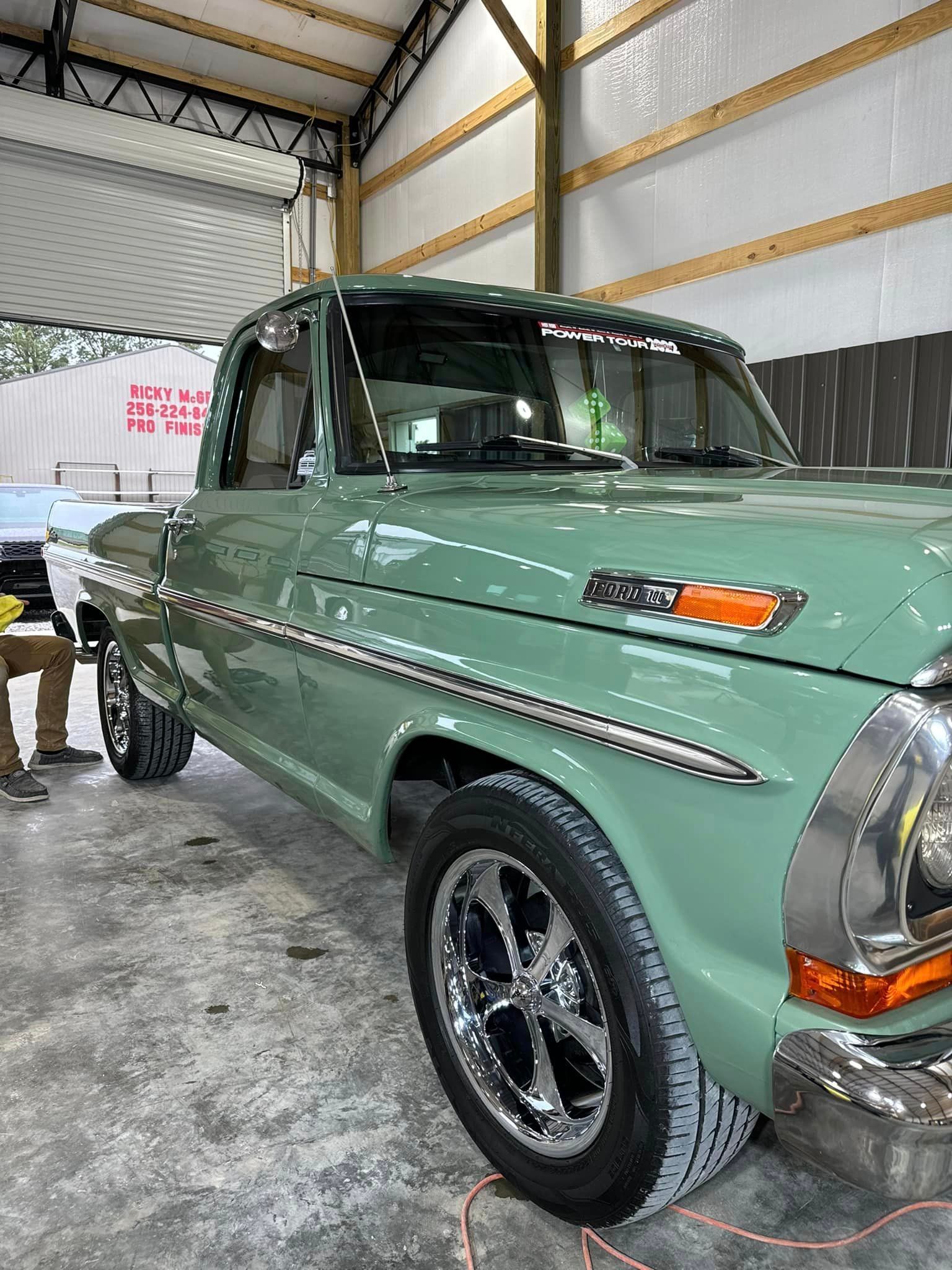A green pickup truck is parked in a garage.