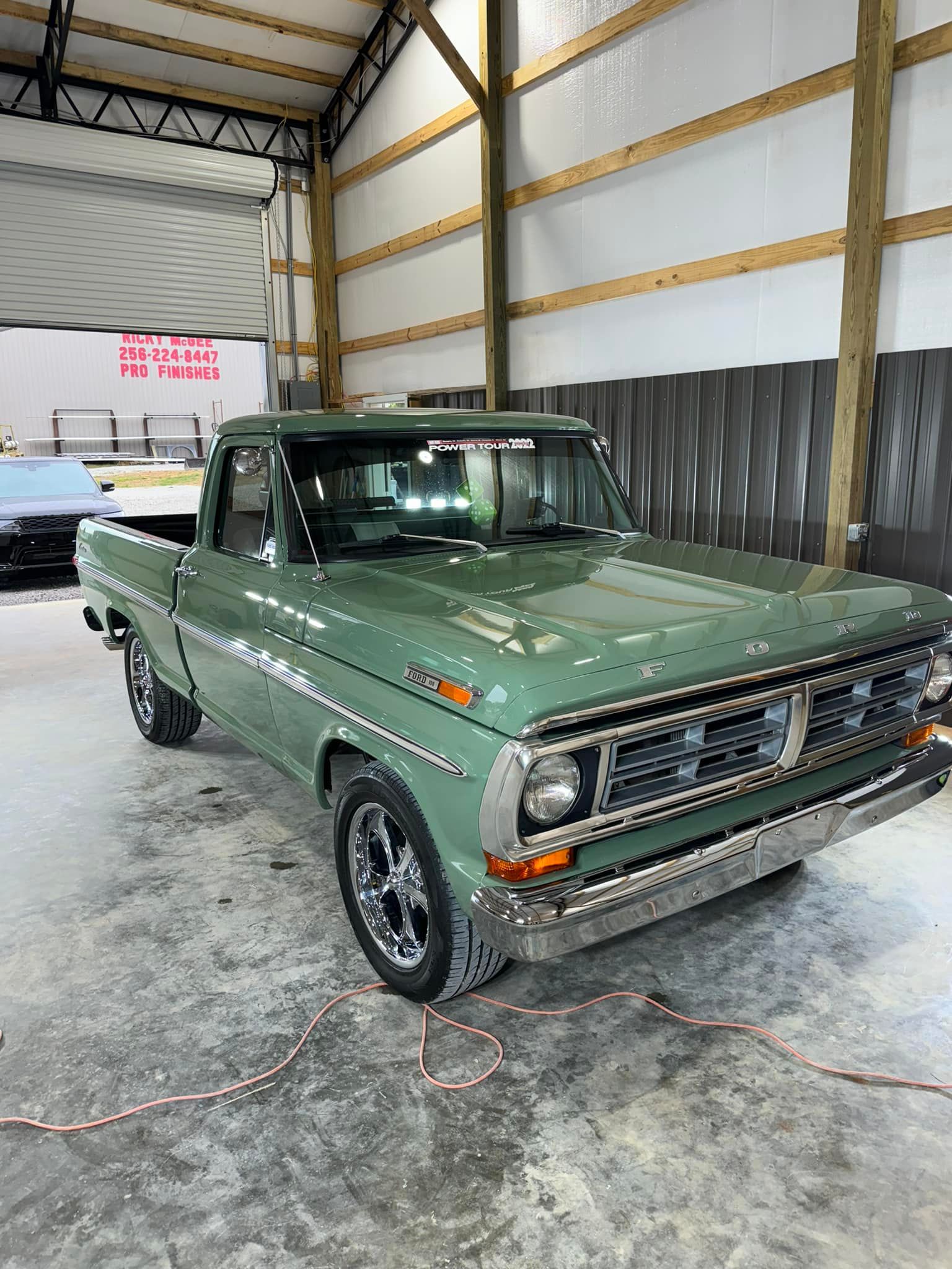 A green pickup truck is parked in a garage.