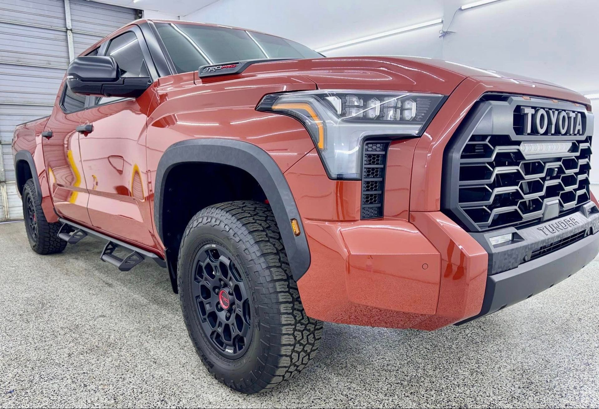 A red toyota tundra is parked in a garage.