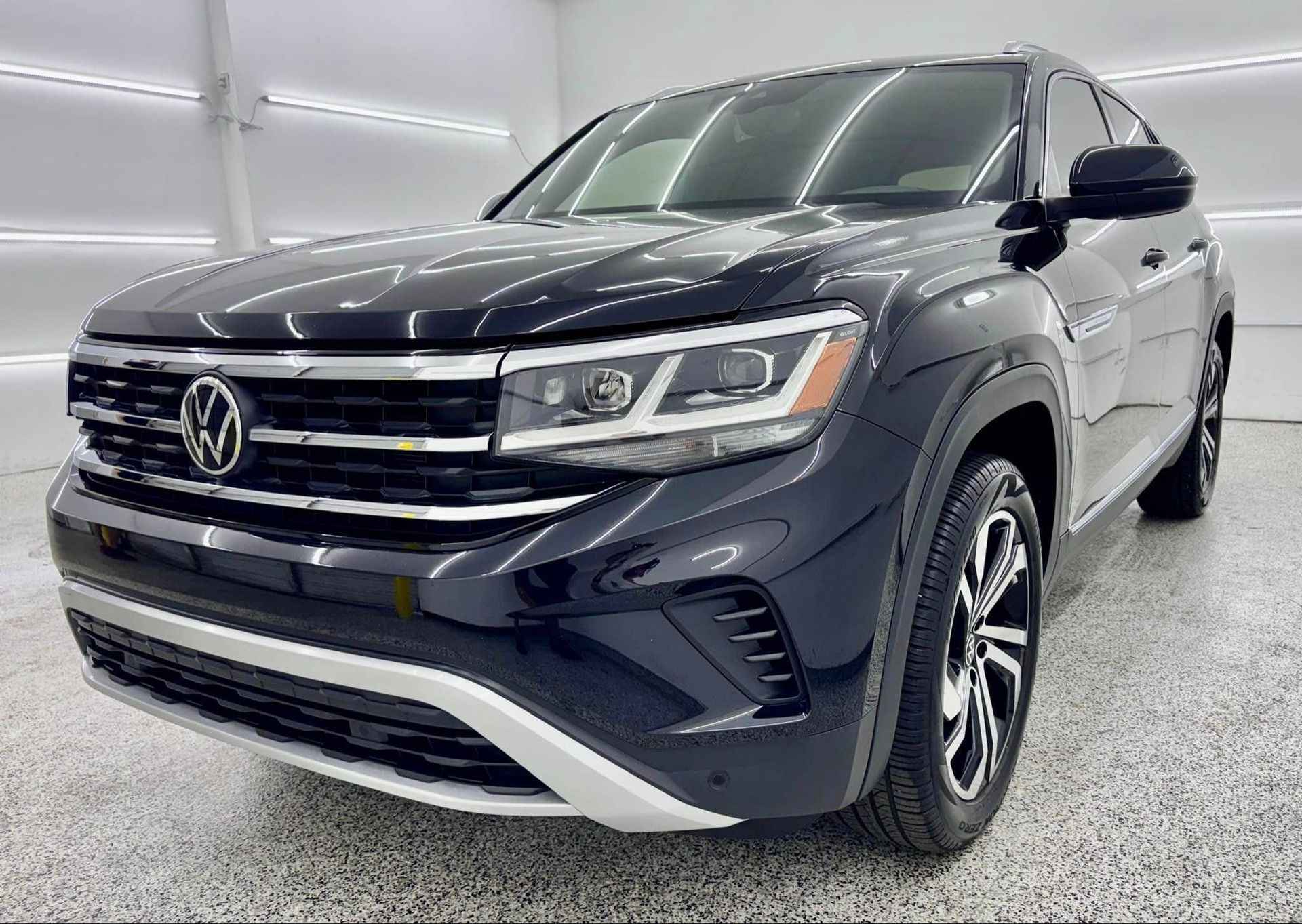 A black volkswagen atlas is parked in a showroom.
