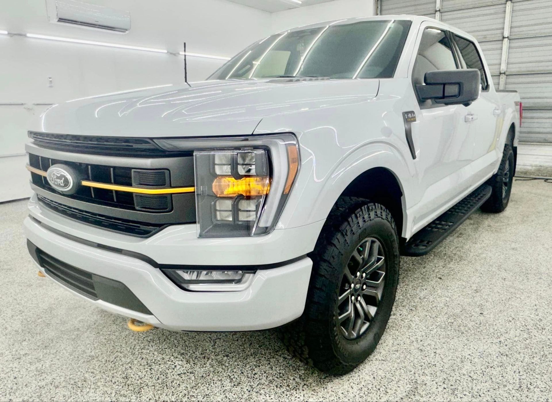 A white ford f150 truck is parked in a garage.