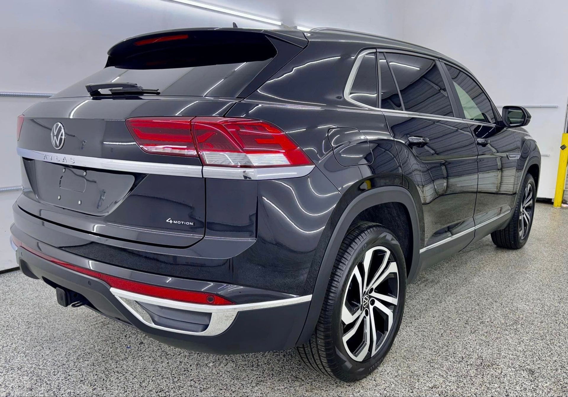 A black volkswagen atlas is parked in a garage.