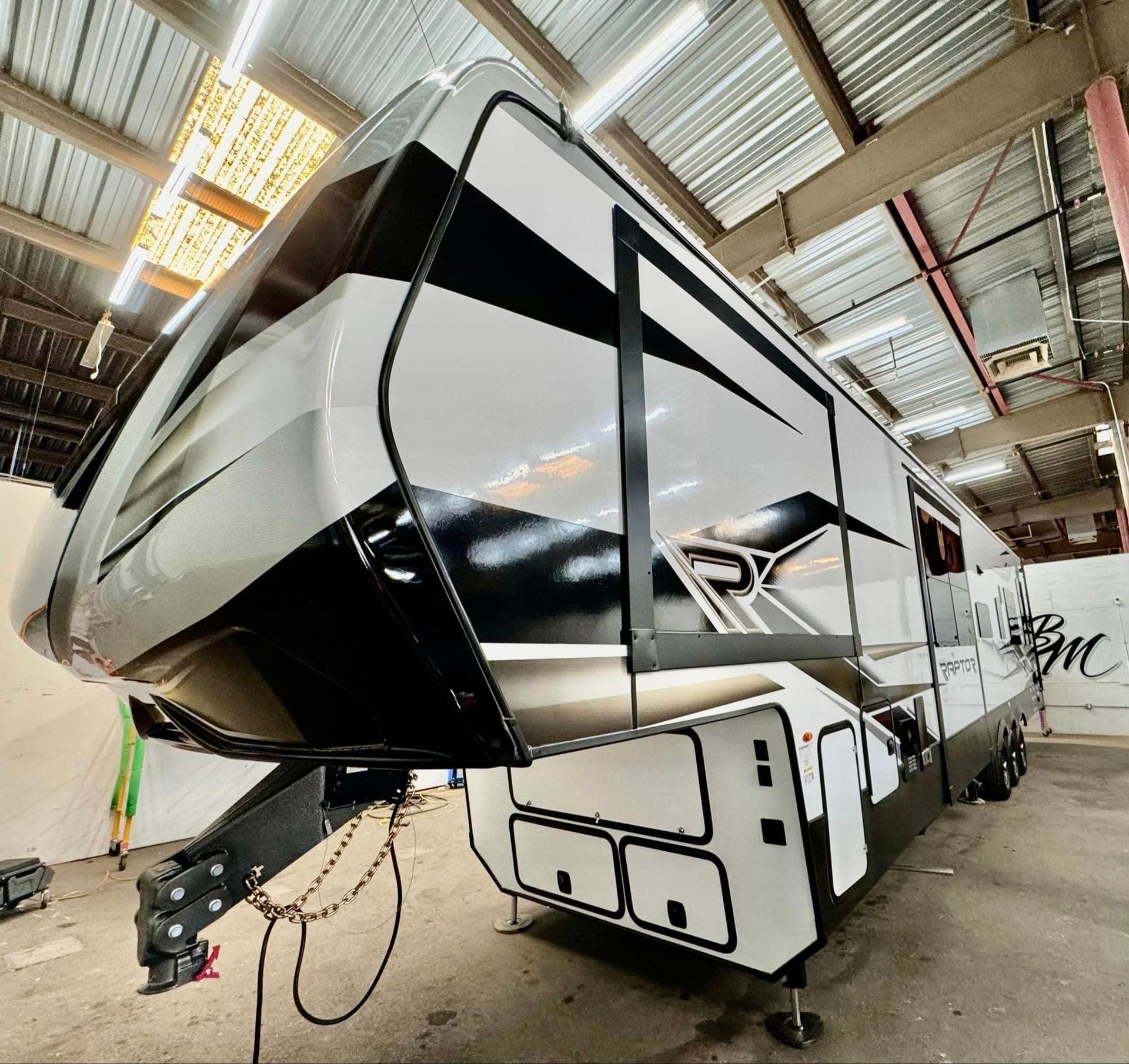A black and white trailer is parked in a warehouse with Bob Moses ceramic coating, Sensha World Crystal Glow