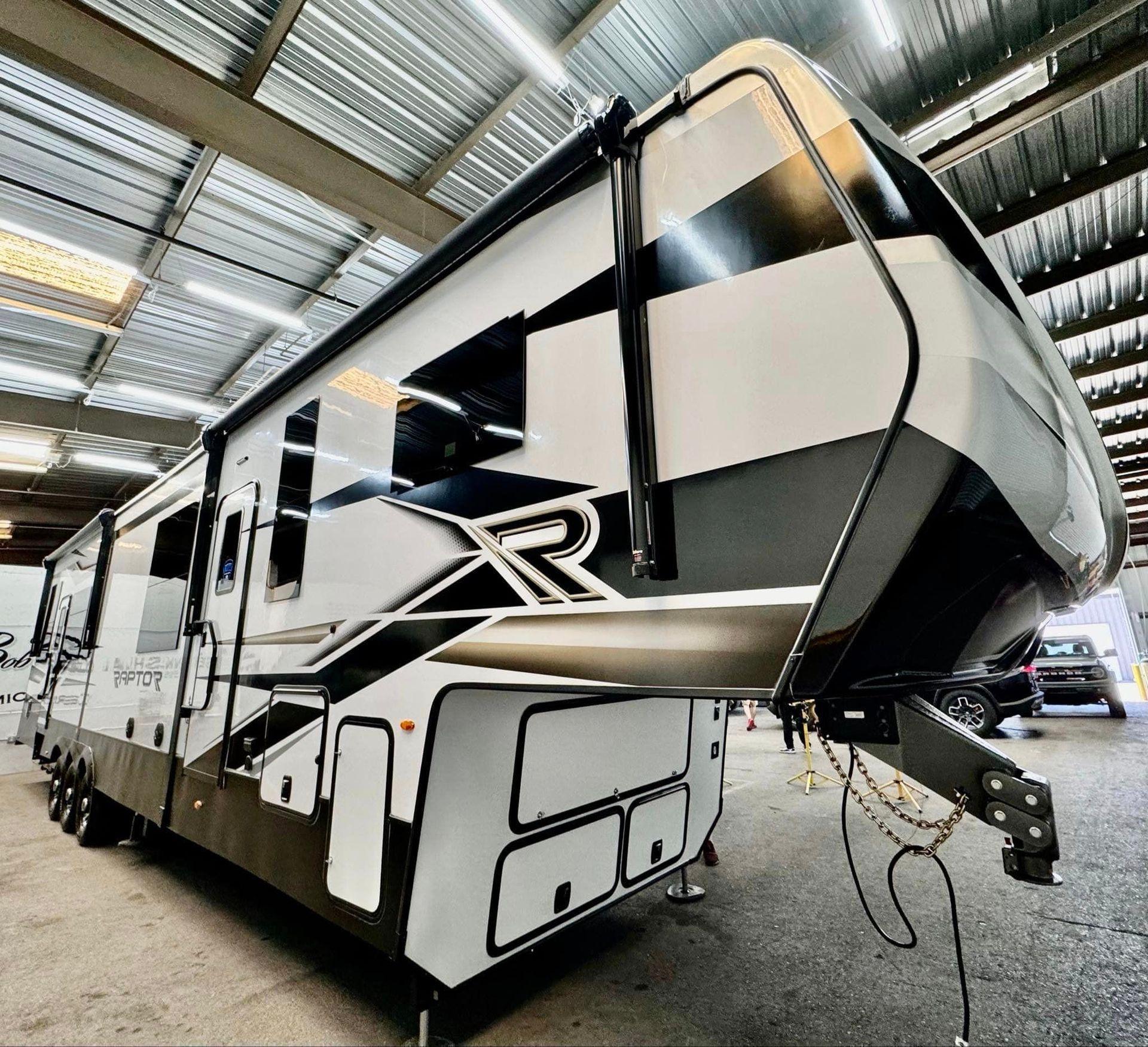 A black and white rv is parked in a warehouse with Bob Moses ceramic coating, Sensha World Crystal Glow