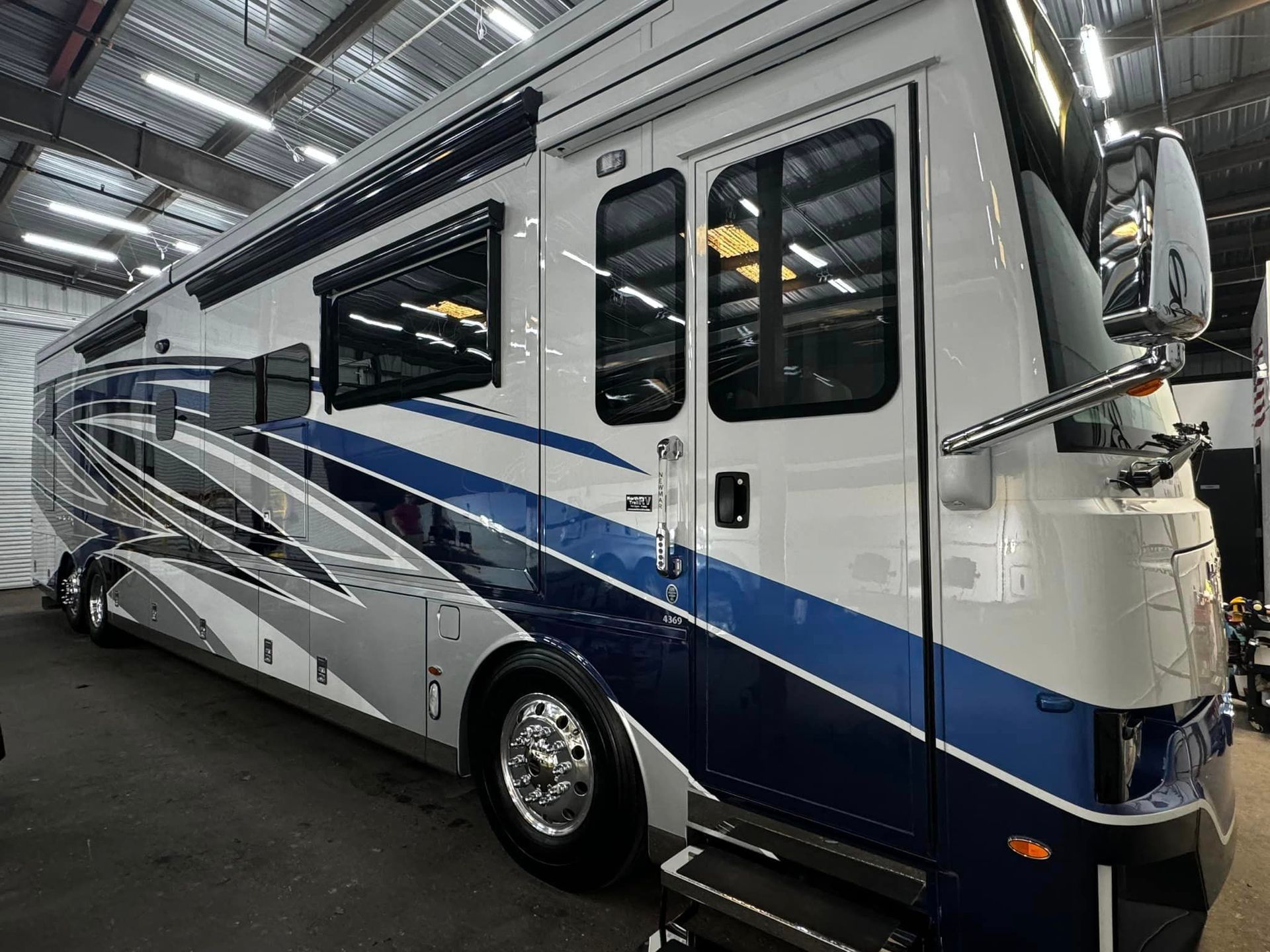 A large blue and white rv is parked in a garage with Bob Moses ceramic coating, Sensha World Crystal Glow