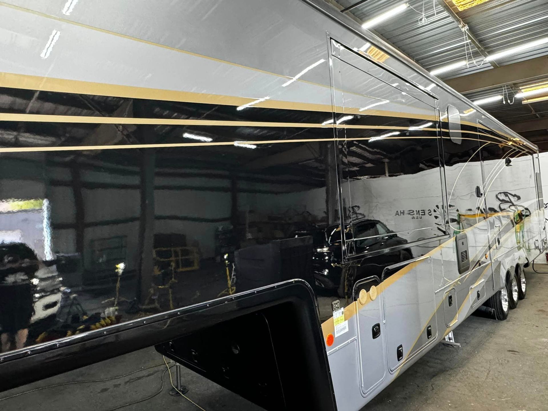 A large trailer is sitting in a garage with Bob Moses ceramic coating, Sensha World Crystal Glow